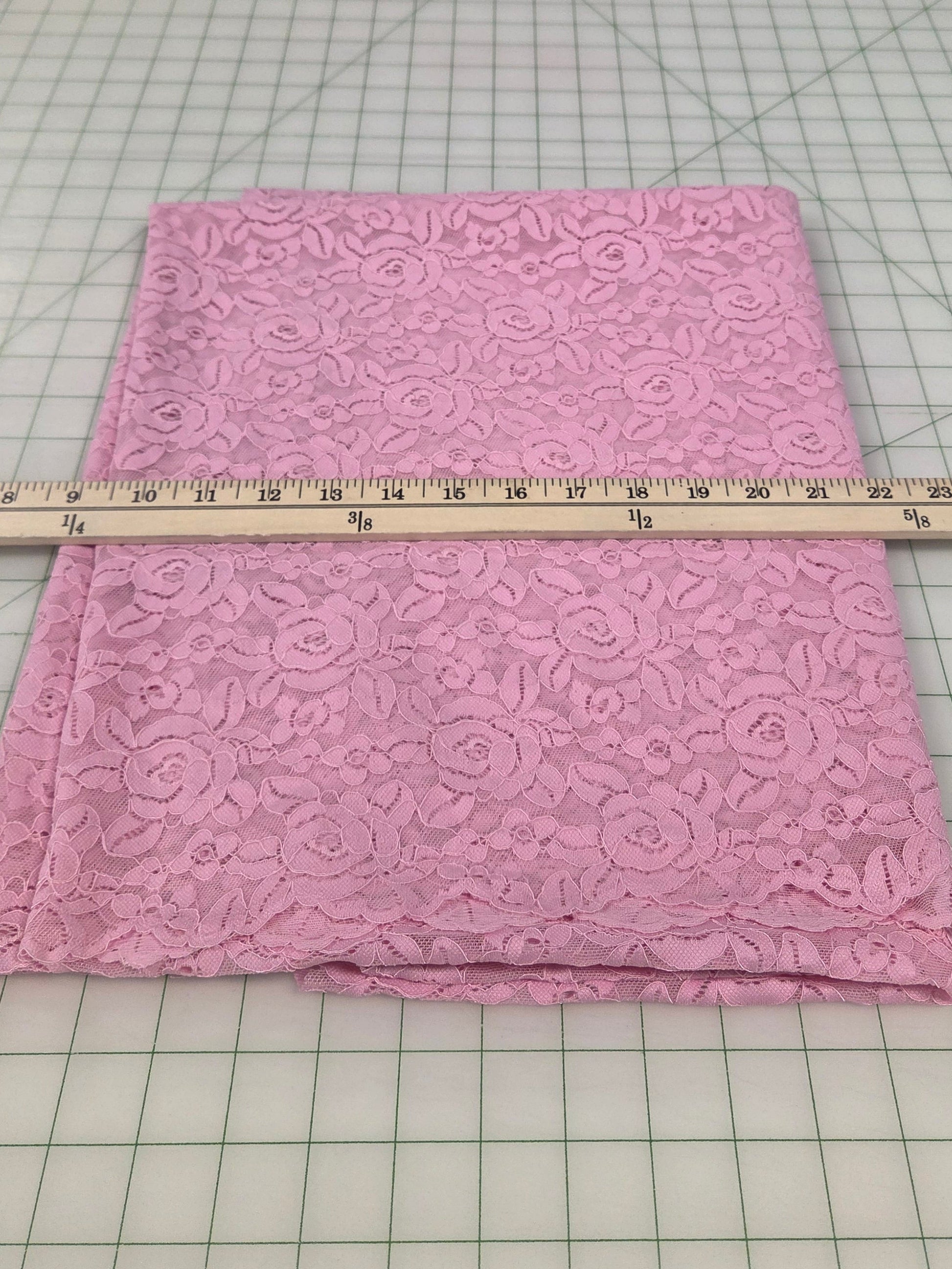 Pink fabric with a pattern on a cutting mat with a ruler for measurement.