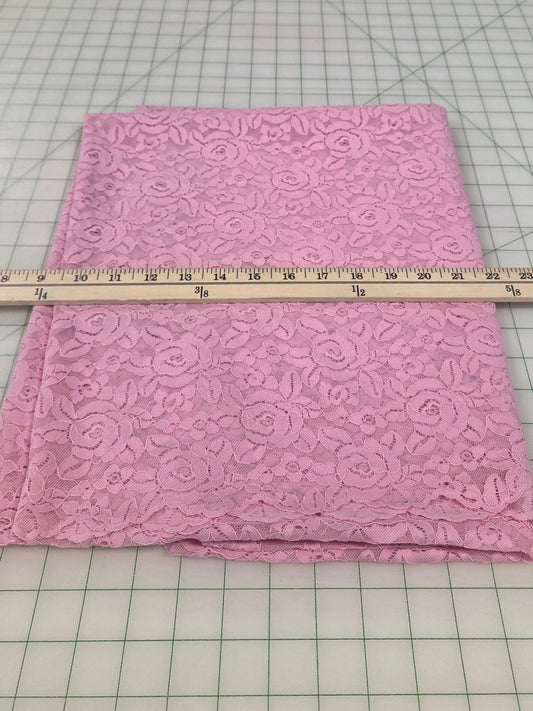 Pink fabric with a pattern on a cutting mat with a ruler for measurement.