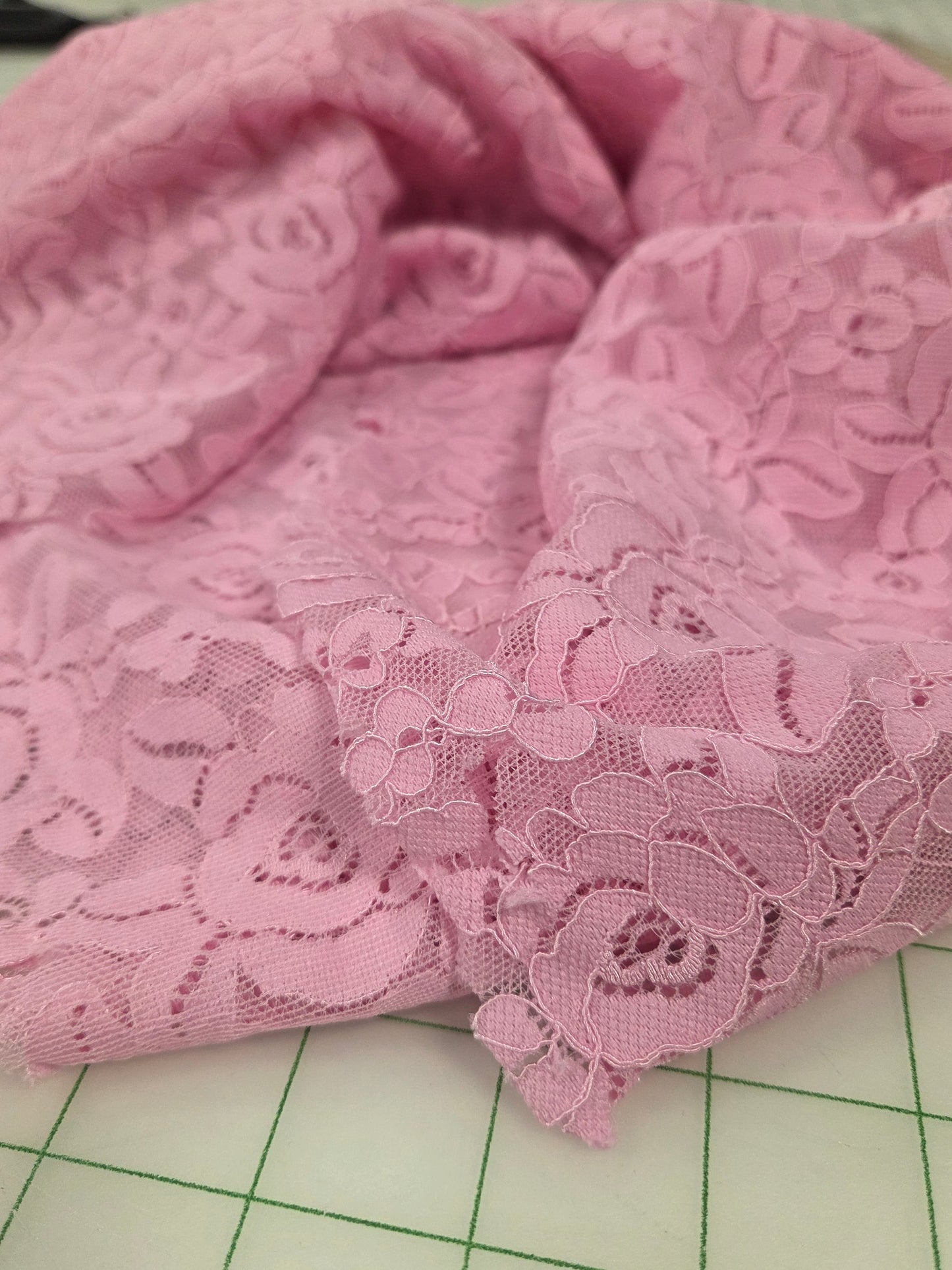 Pink lace fabric on a green cutting mat