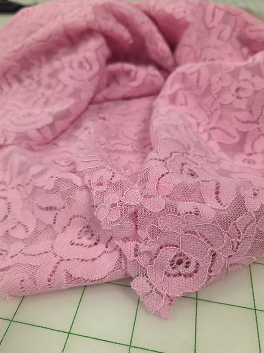 Pink lace fabric on a green cutting mat