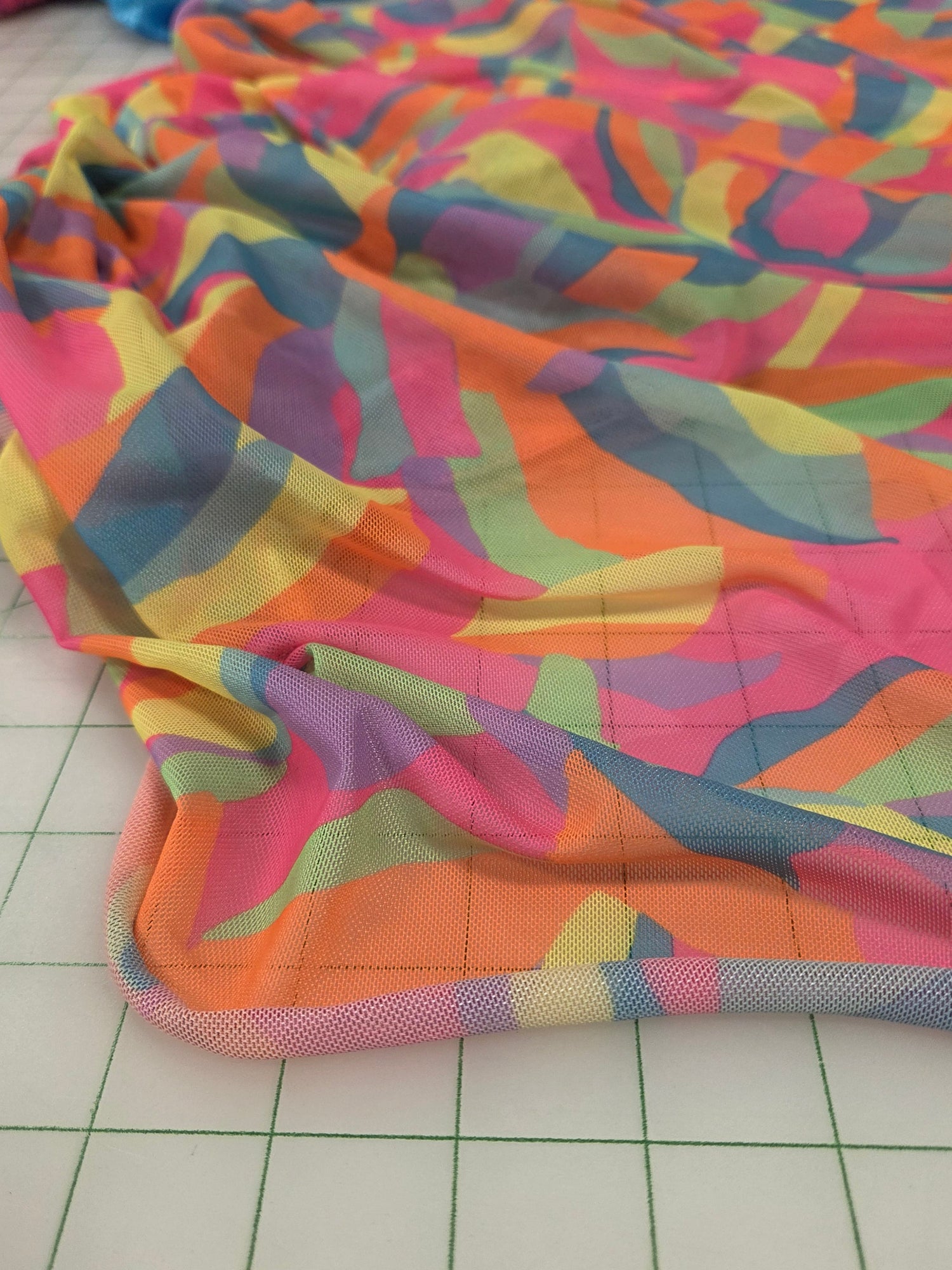 Colorful patterned fabric on a grid background . LA Finch Fabrics. Vibrant Mesh Knit