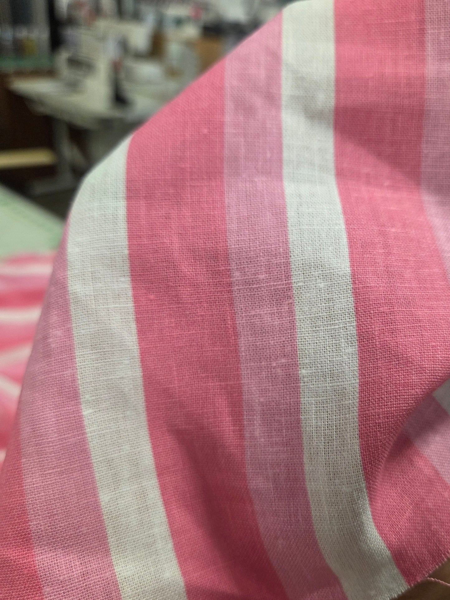 Close-up of a pink and white striped fabric with a blurred background. Stripe fabric pink LA Finch Fabrics. Deadstock fabric.