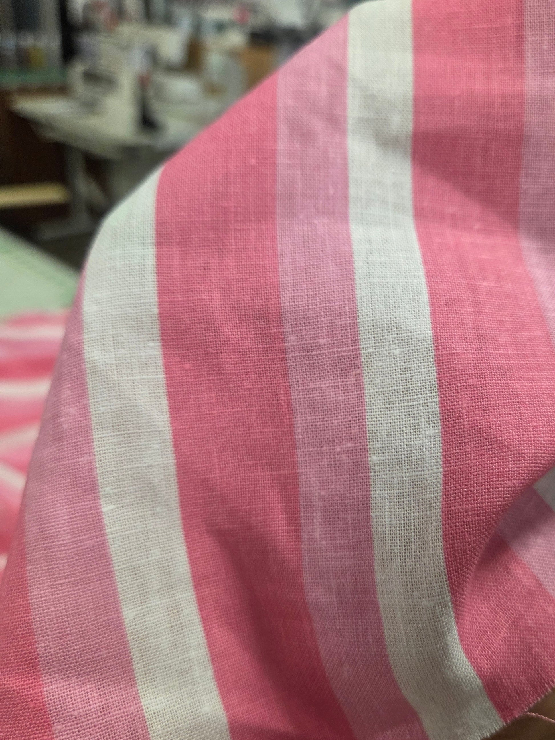 Close-up of a pink and white striped fabric with a blurred background. Stripe fabric pink LA Finch Fabrics. Deadstock fabric.