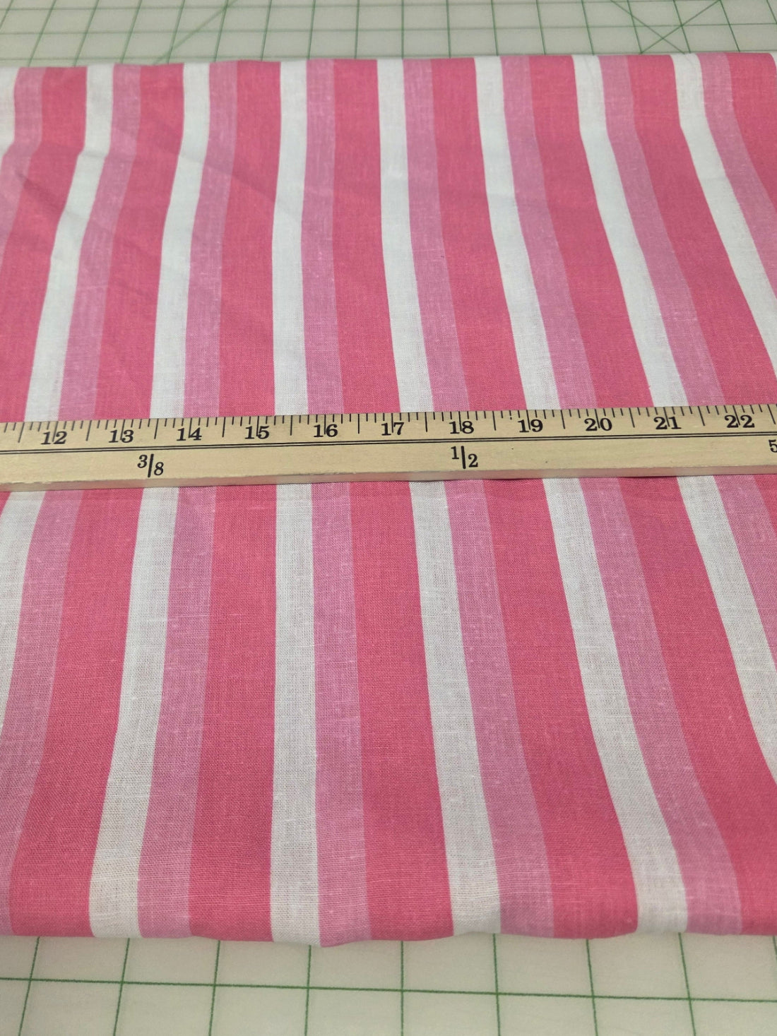 Striped fabric with a ruler for scale on a grid background. rayon  linen barbie pink stripe
