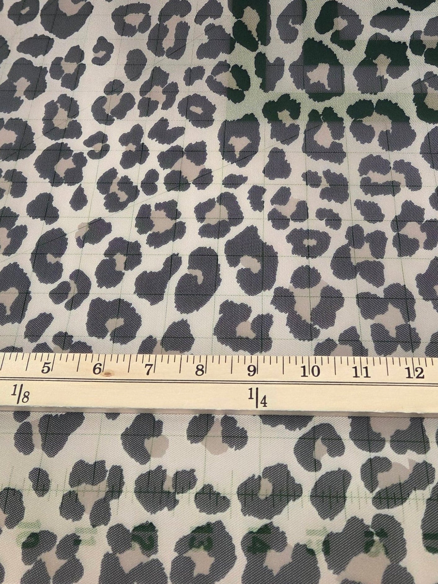 Leopard print fabric with a ruler for scale on a beige background. LA Finch Fabrics. Deadstock Mesh Knit