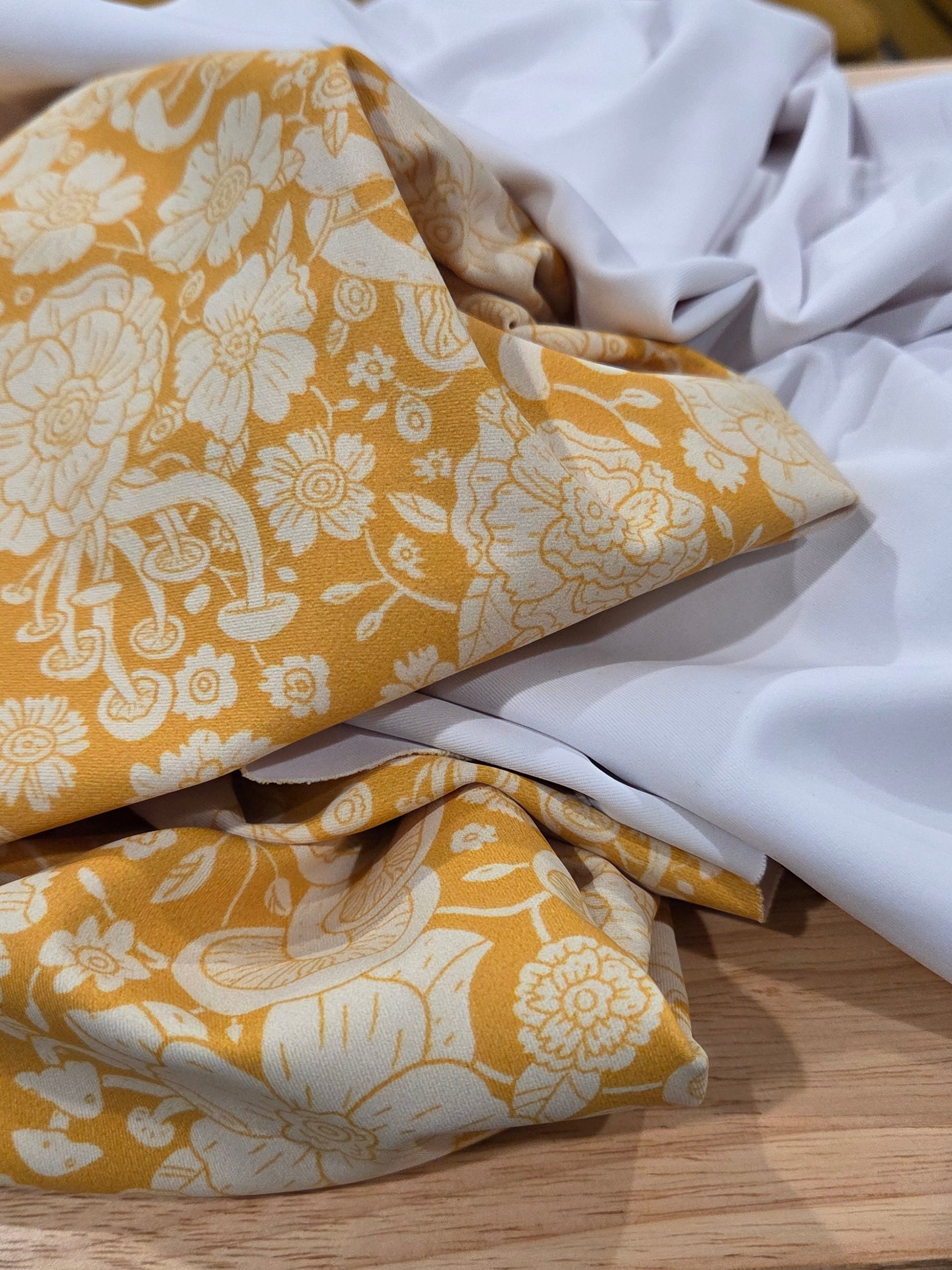 Yellow floral fabric on a wooden surface with white cloth underneath