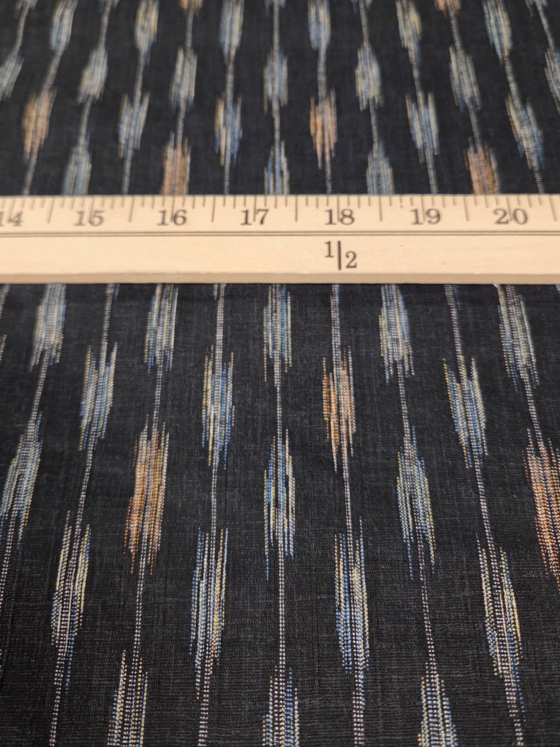 Fabric with a pattern and a ruler for scale on a grid background