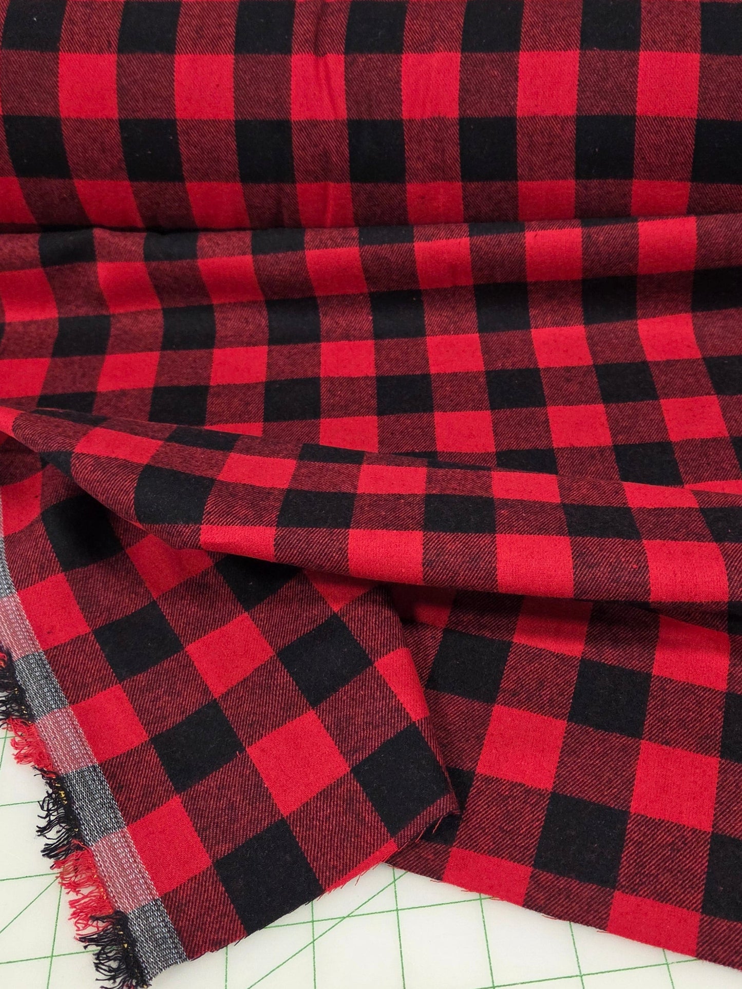 Red and black checkered fabric on a cutting mat