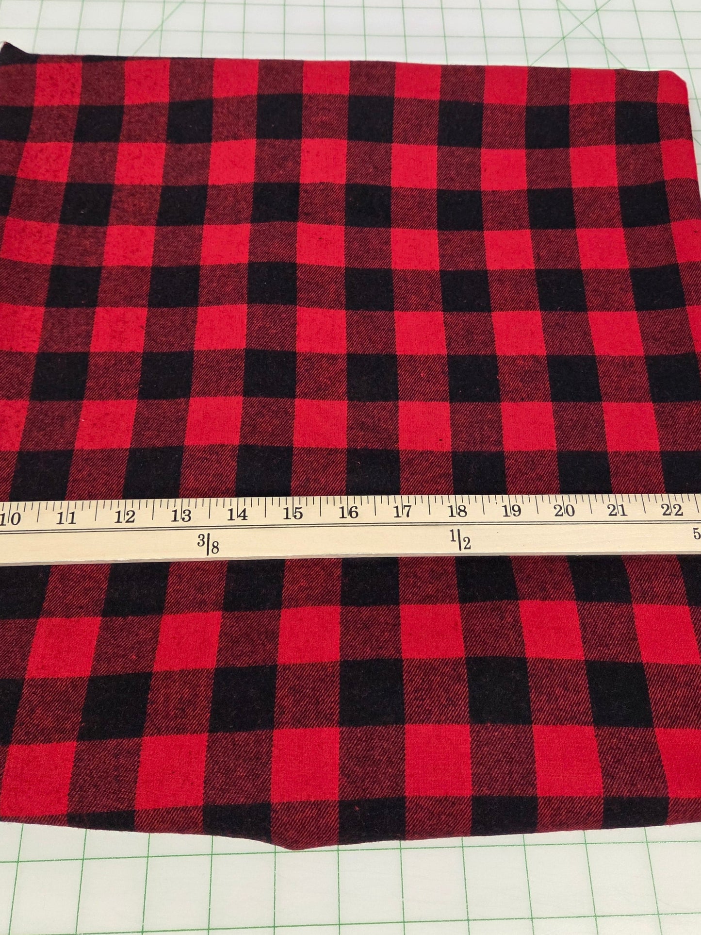 Red and black checkered fabric with a measuring tape on a grid background