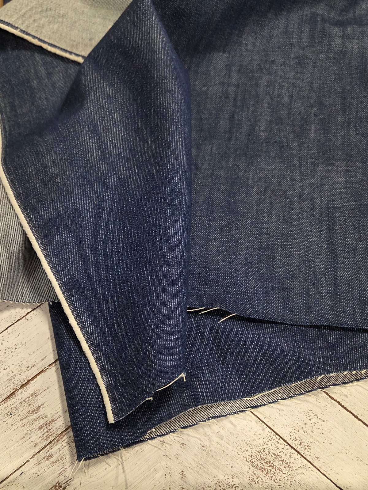 Blue denim fabric on a wooden surface with a ruler for scale.