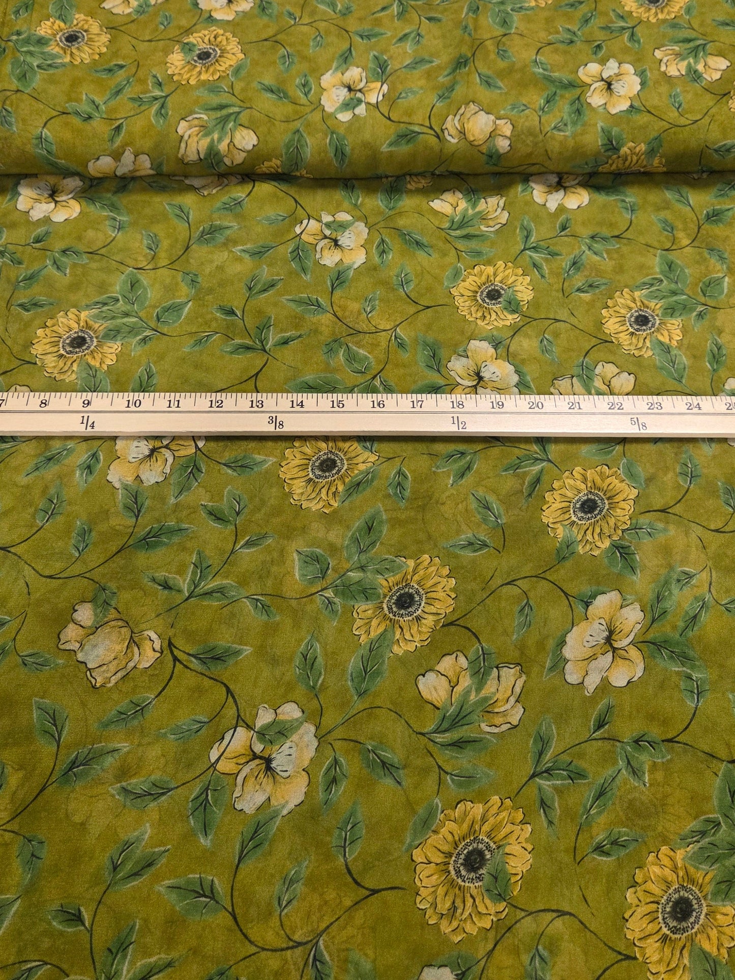 Roll of green floral fabric with a measuring tape alongside