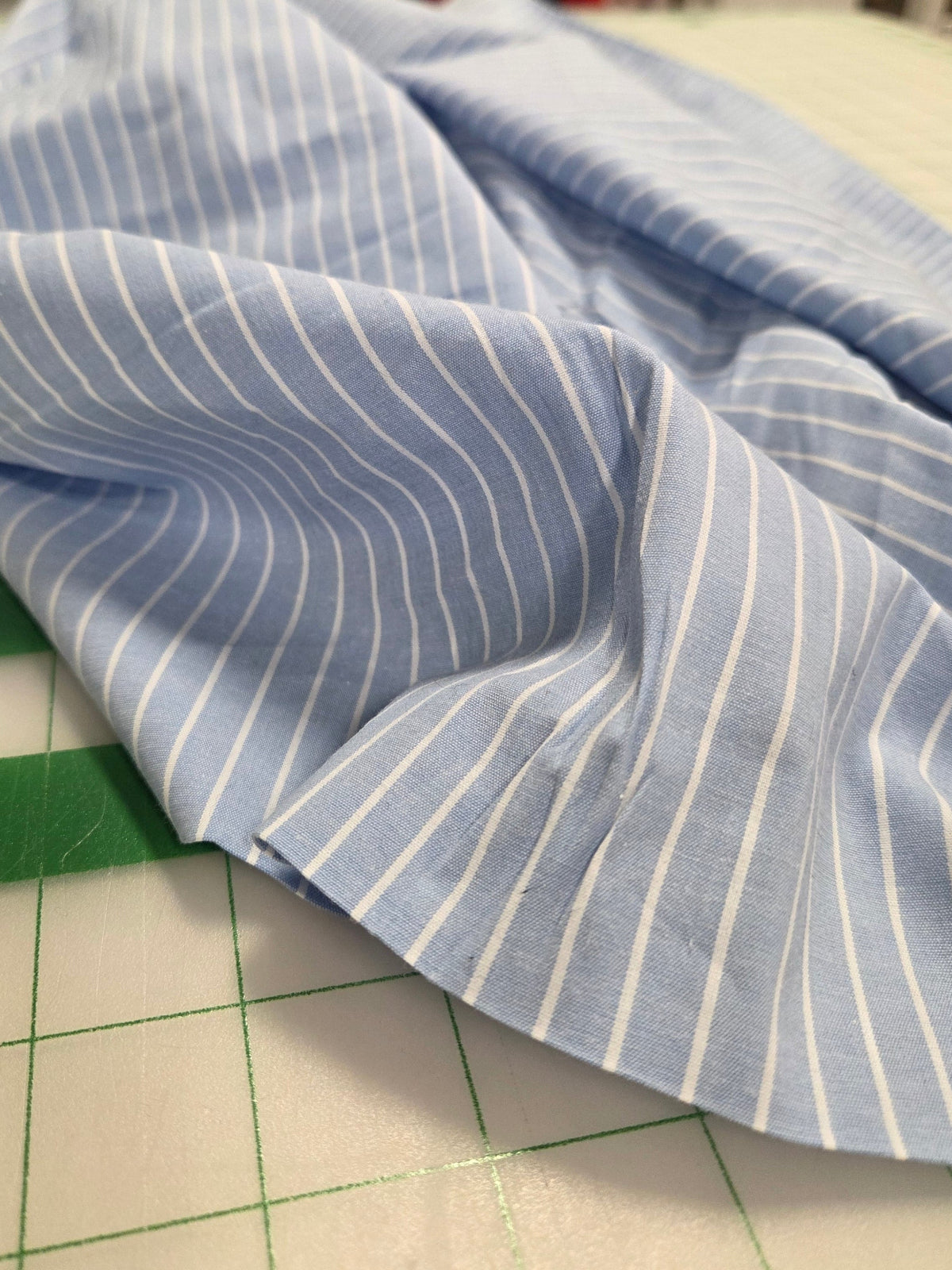 Blue and white striped fabric on a cutting mat with tools in the background