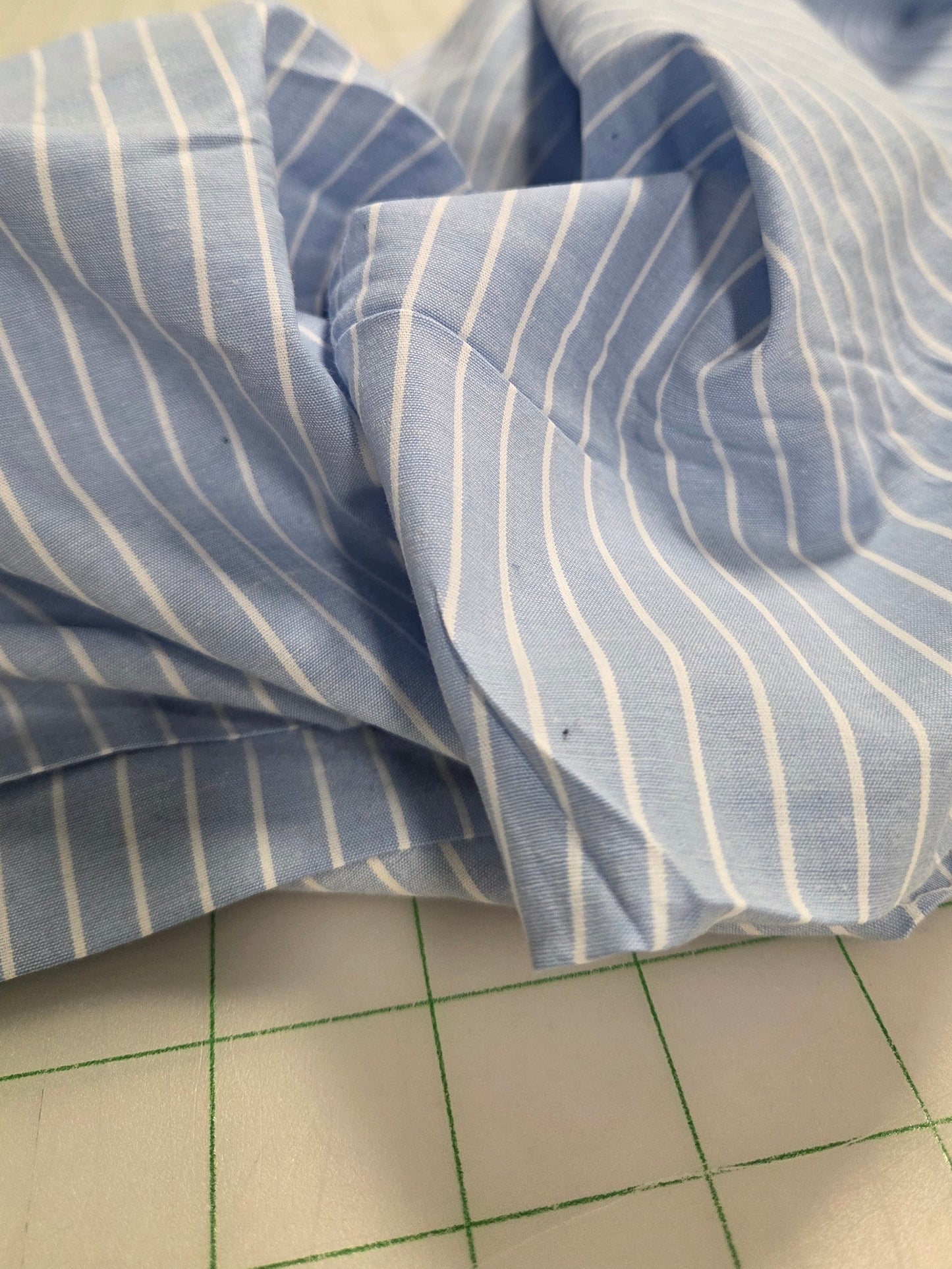 Blue and white striped fabric on a cutting mat with tools in the background