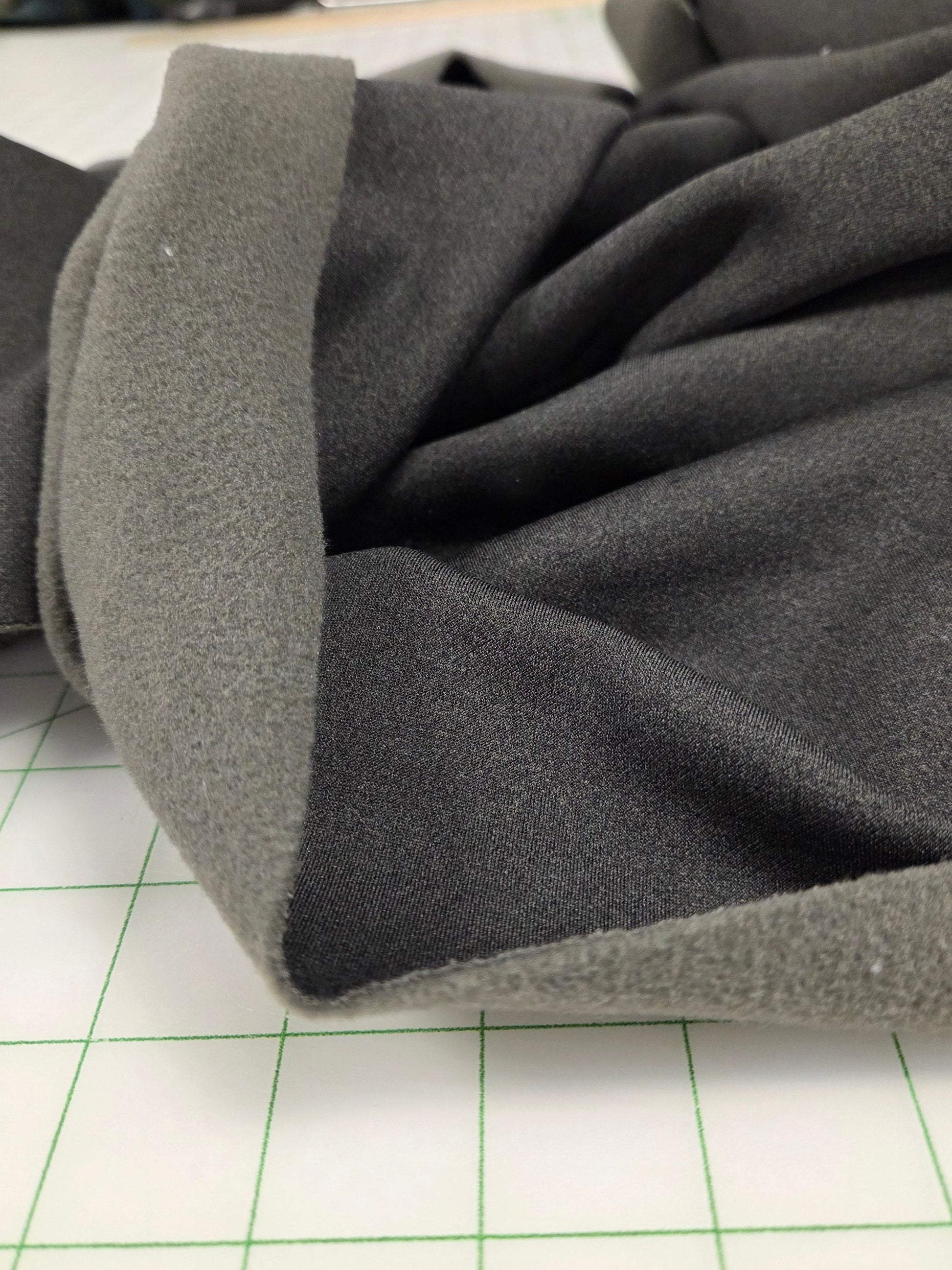 Gray coat with a textured collar against a white background with green grid lines