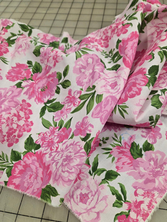 Floral fabric with pink flowers and green leaves on a white background