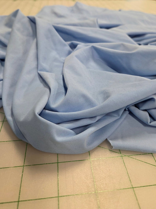 Blue fabric on a cutting mat with a workshop background