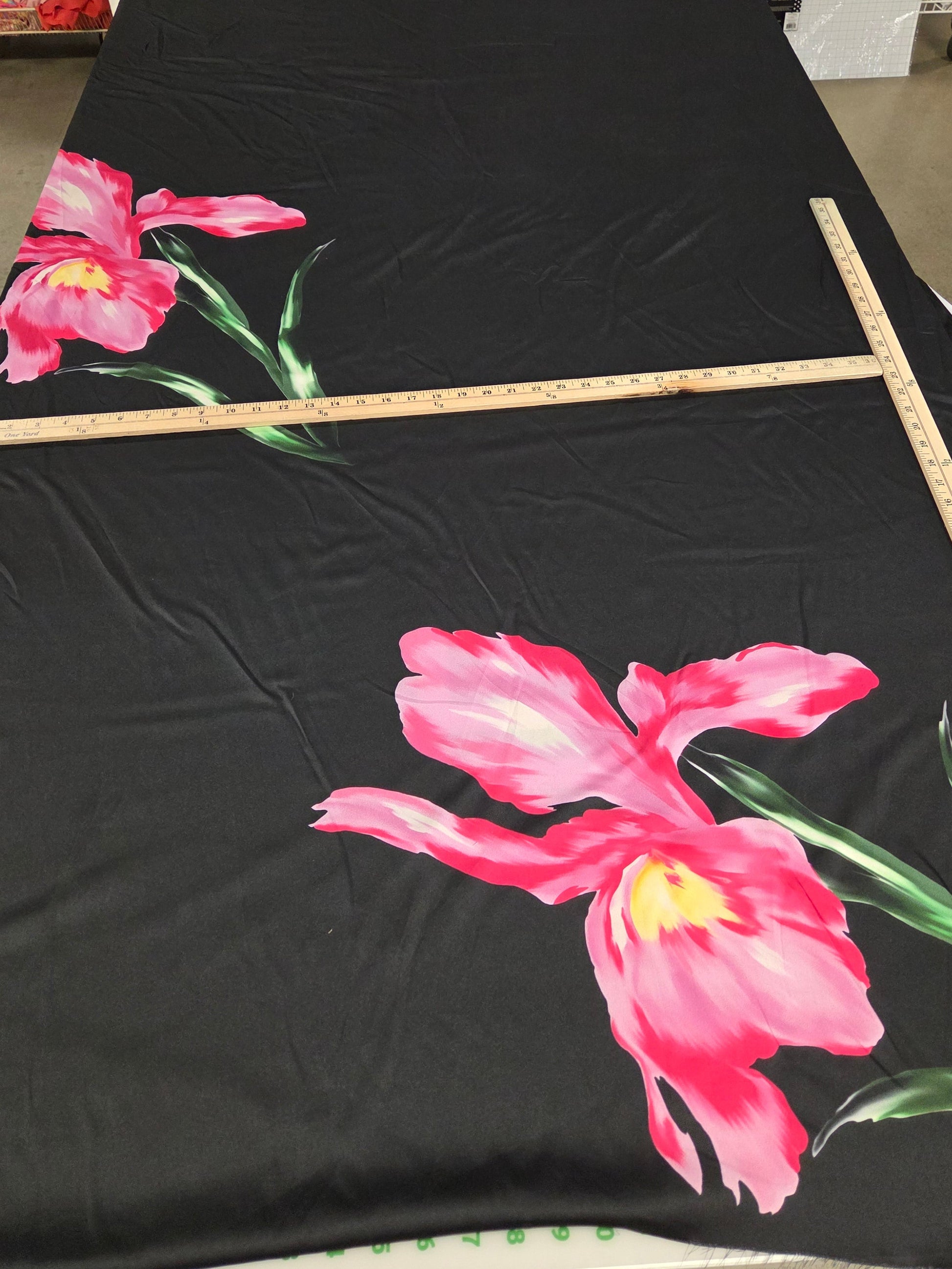 Black fabric with pink floral design on a stand in a room.