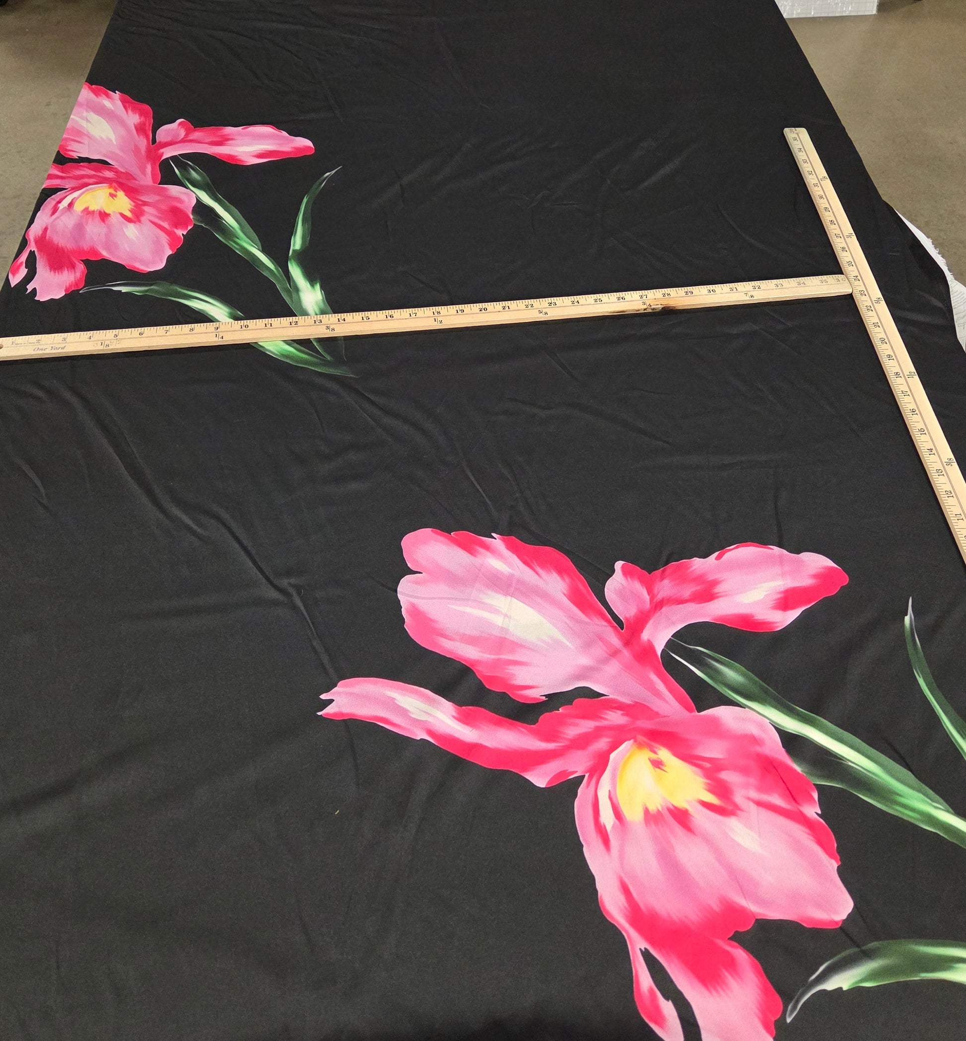 Black fabric with pink floral design on a stand in a room.
