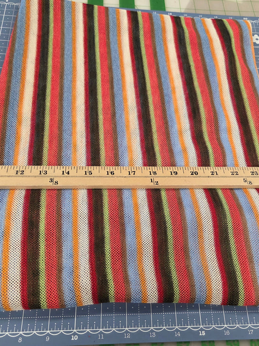 Colorful striped fabric on a cutting mat with a ruler for measurement.