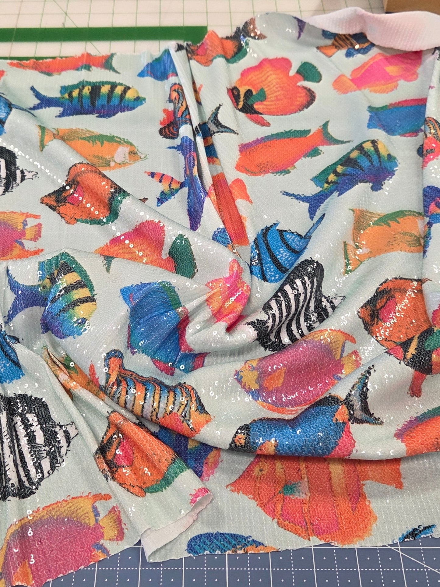 Colorful fish-patterned fabric on a cutting mat with tools in the background