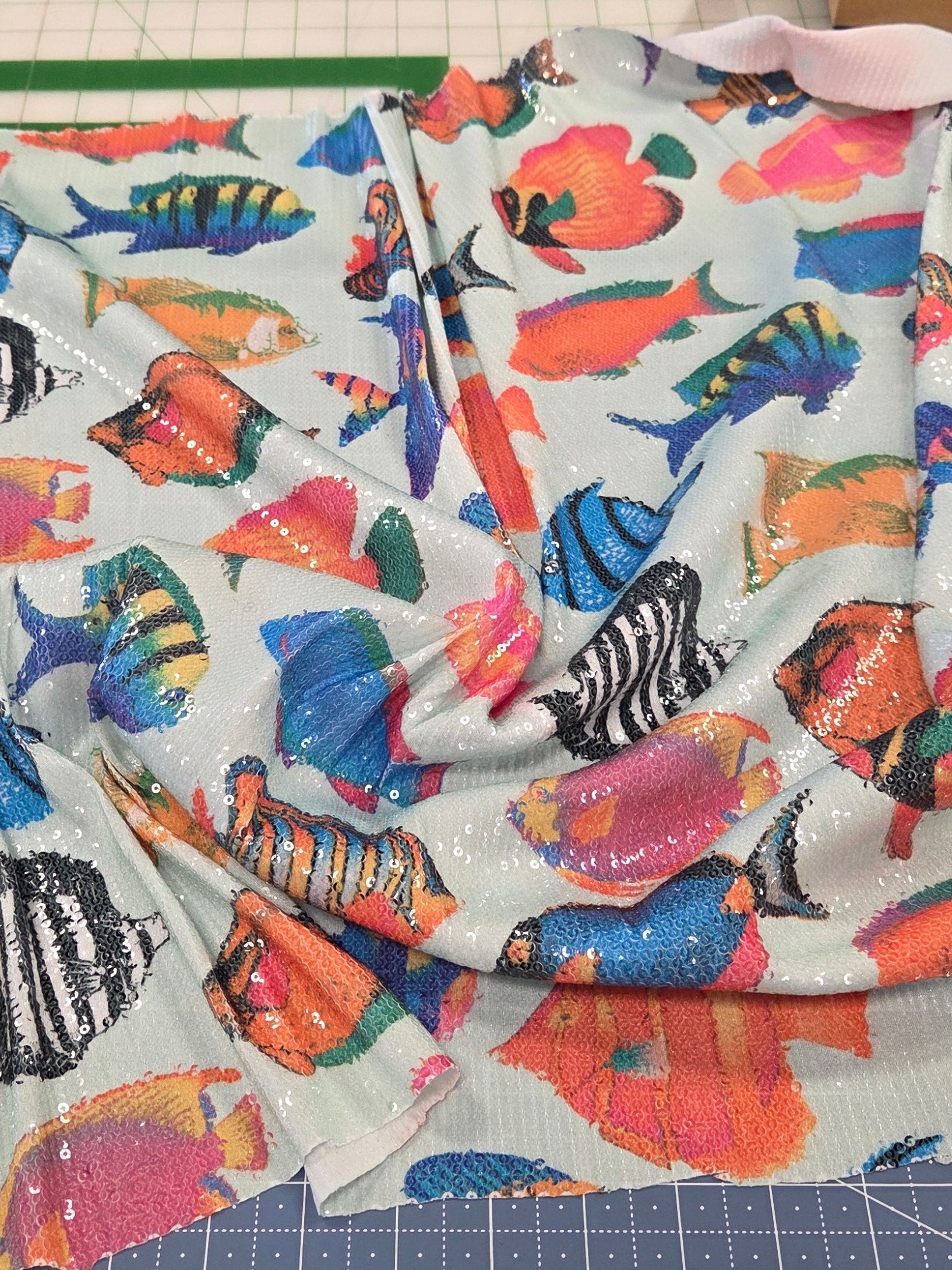 Colorful fish-patterned fabric on a cutting mat with tools in the background