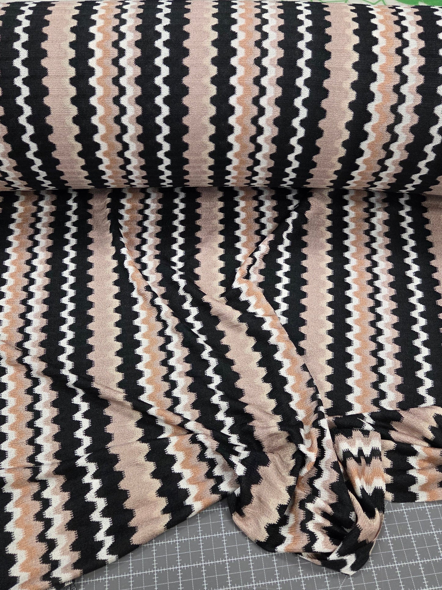 Striped fabric with black, beige, and white pattern on a grid background