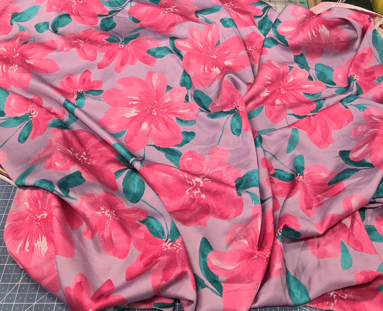 Floral fabric with pink flowers and green  teal leaves on a pink background.