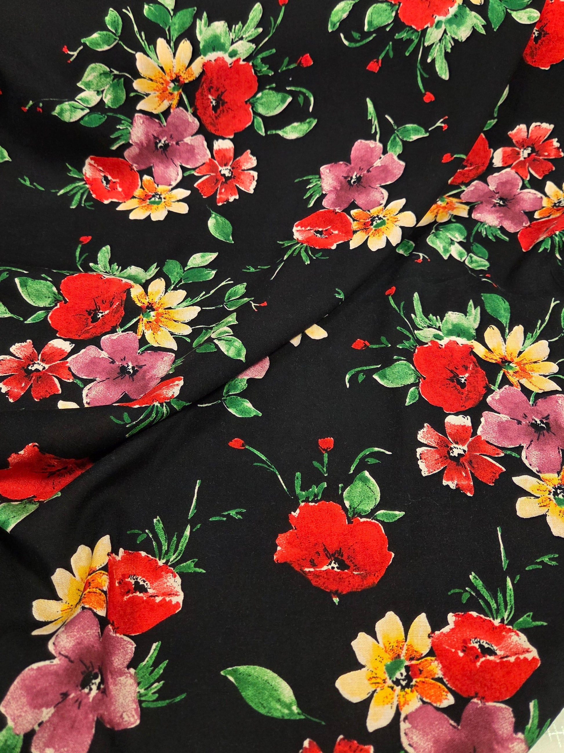 Floral fabric with red, pink, and yellow flowers on a black background