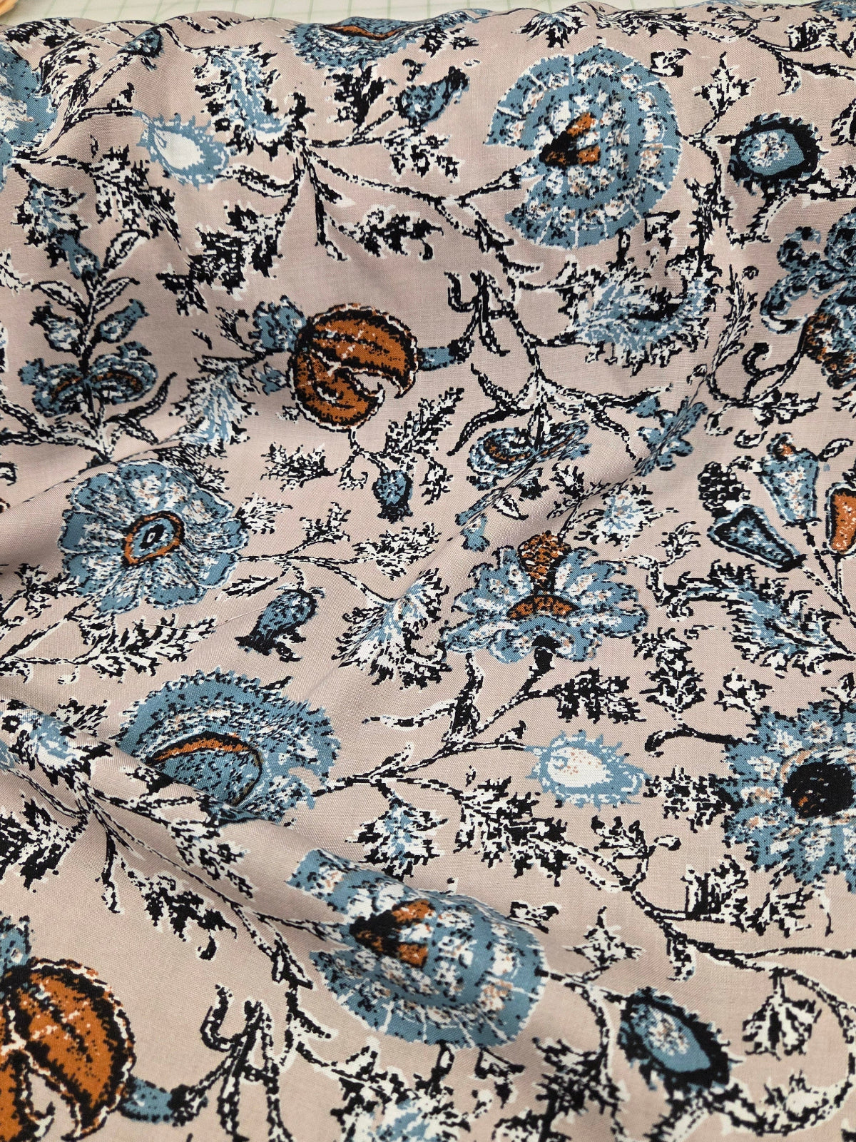 Close-up of floral fabric with blue and brown flowers on a beige background