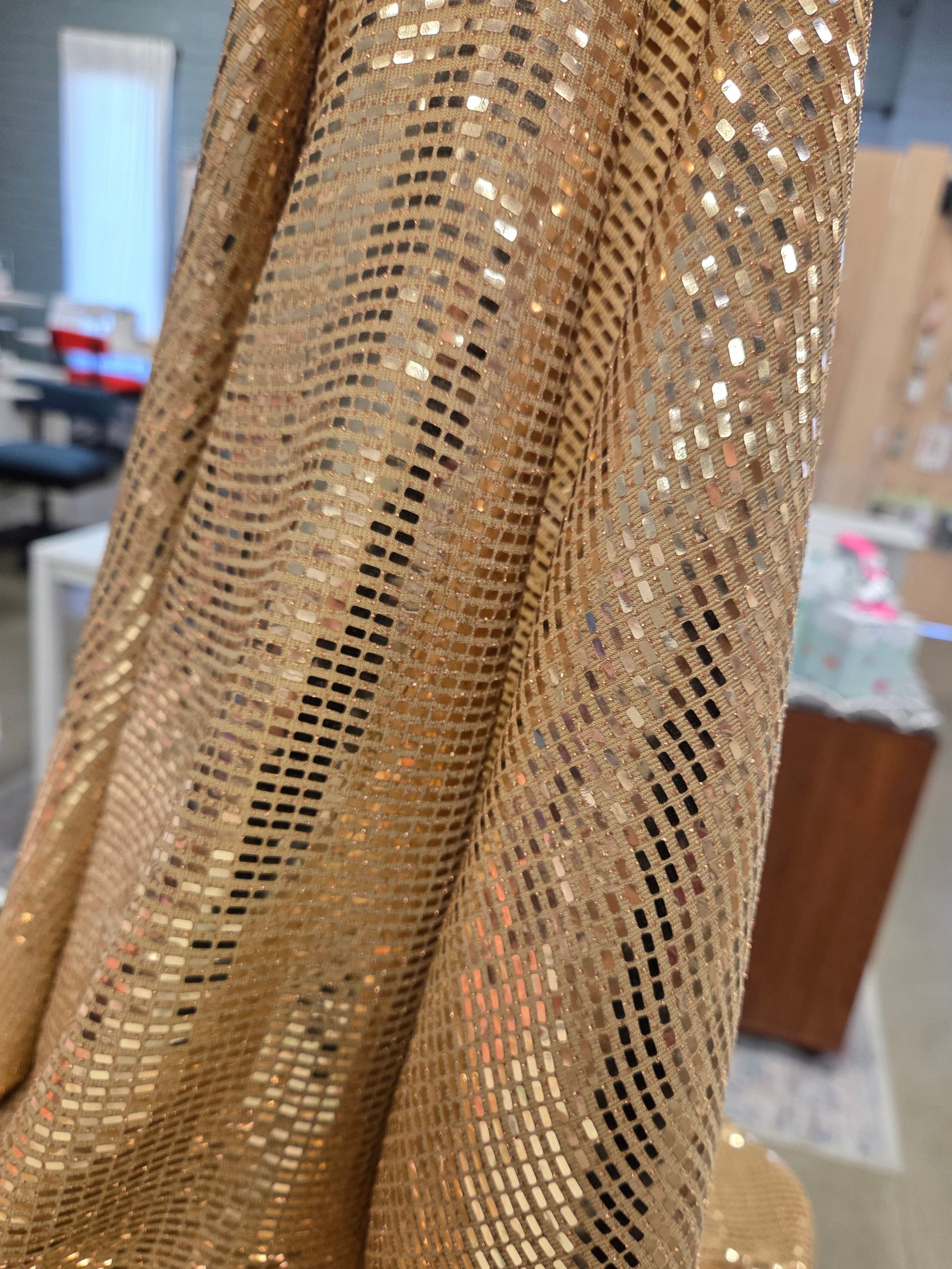 Close-up of gold sequin fabric with a blurred indoor background