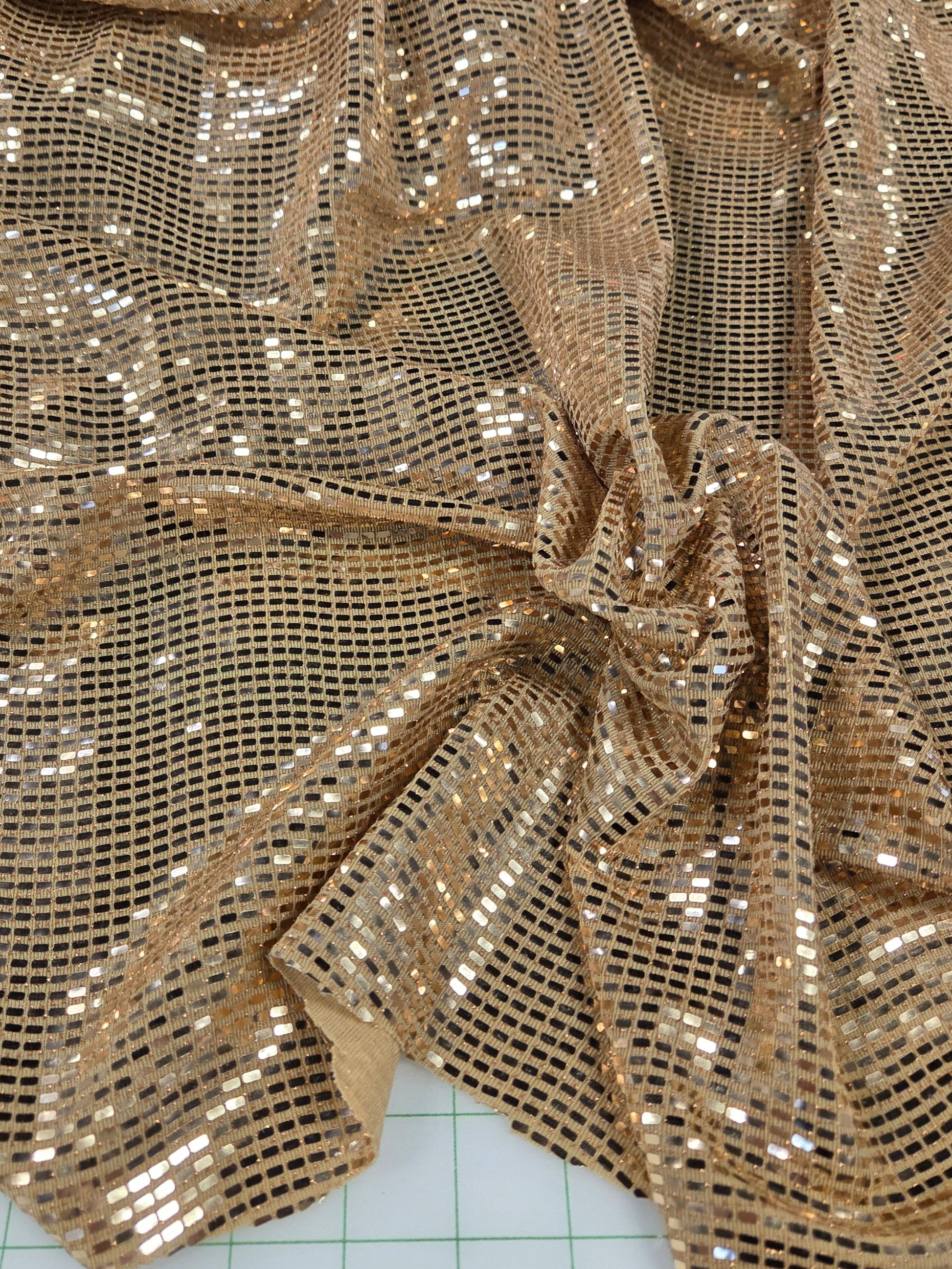 Gold sequin fabric on a cutting mat