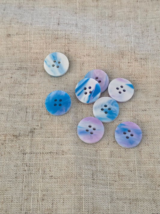 Set of blue and white buttons on a textured beige fabric background