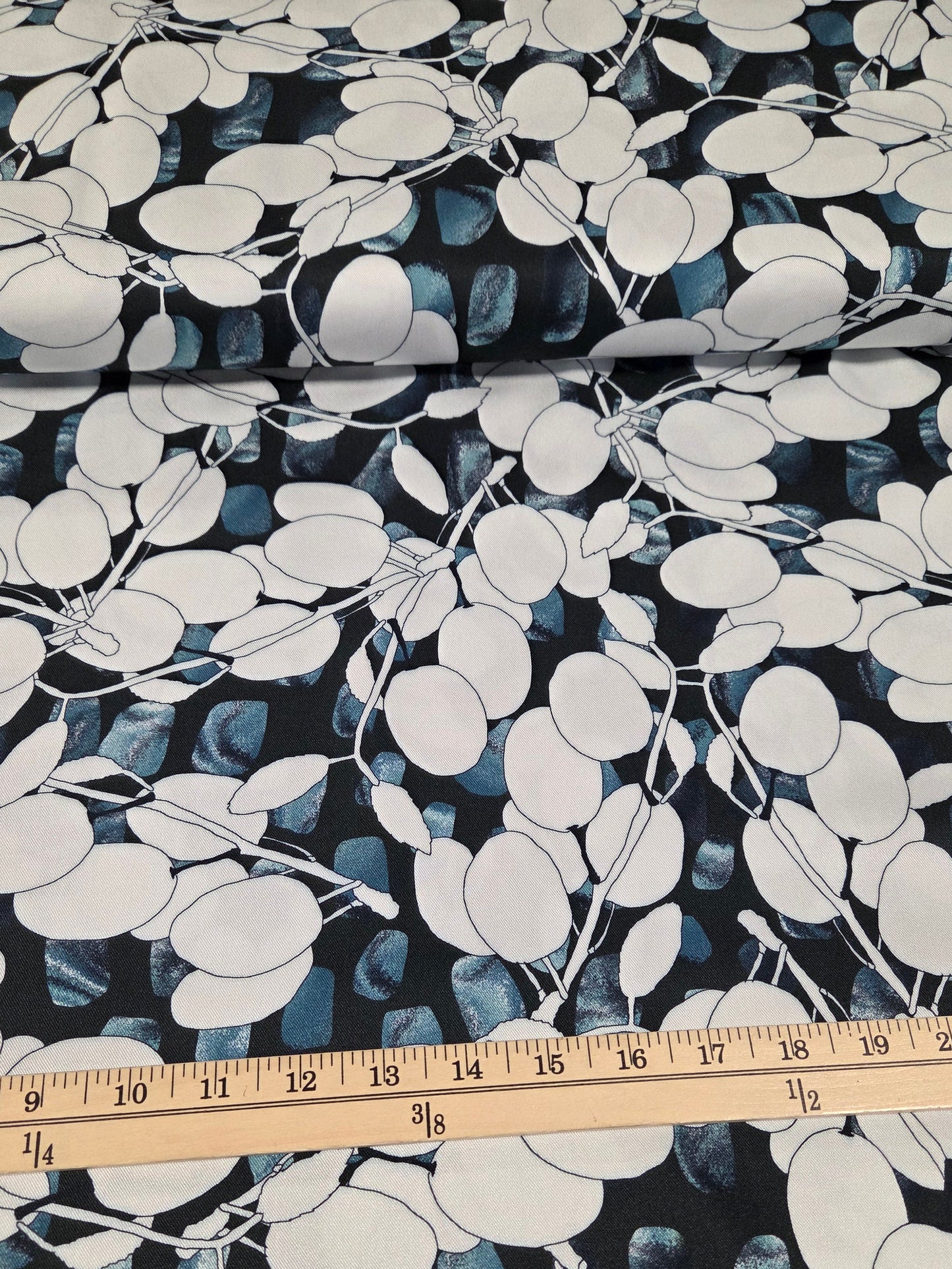 Fabric with a leaf pattern and a ruler for scale on a dark background