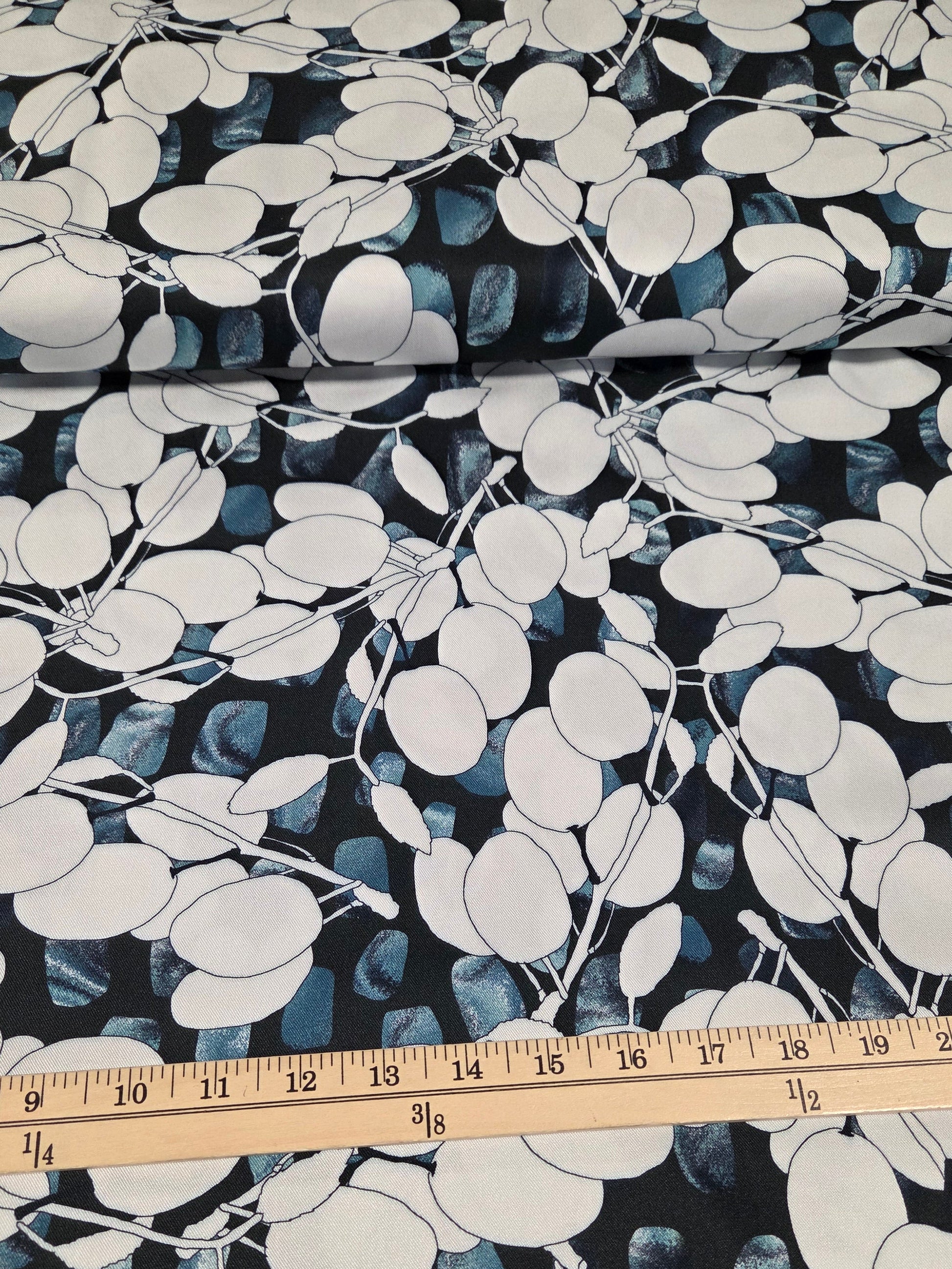 Fabric with a leaf pattern and a ruler for scale on a dark background