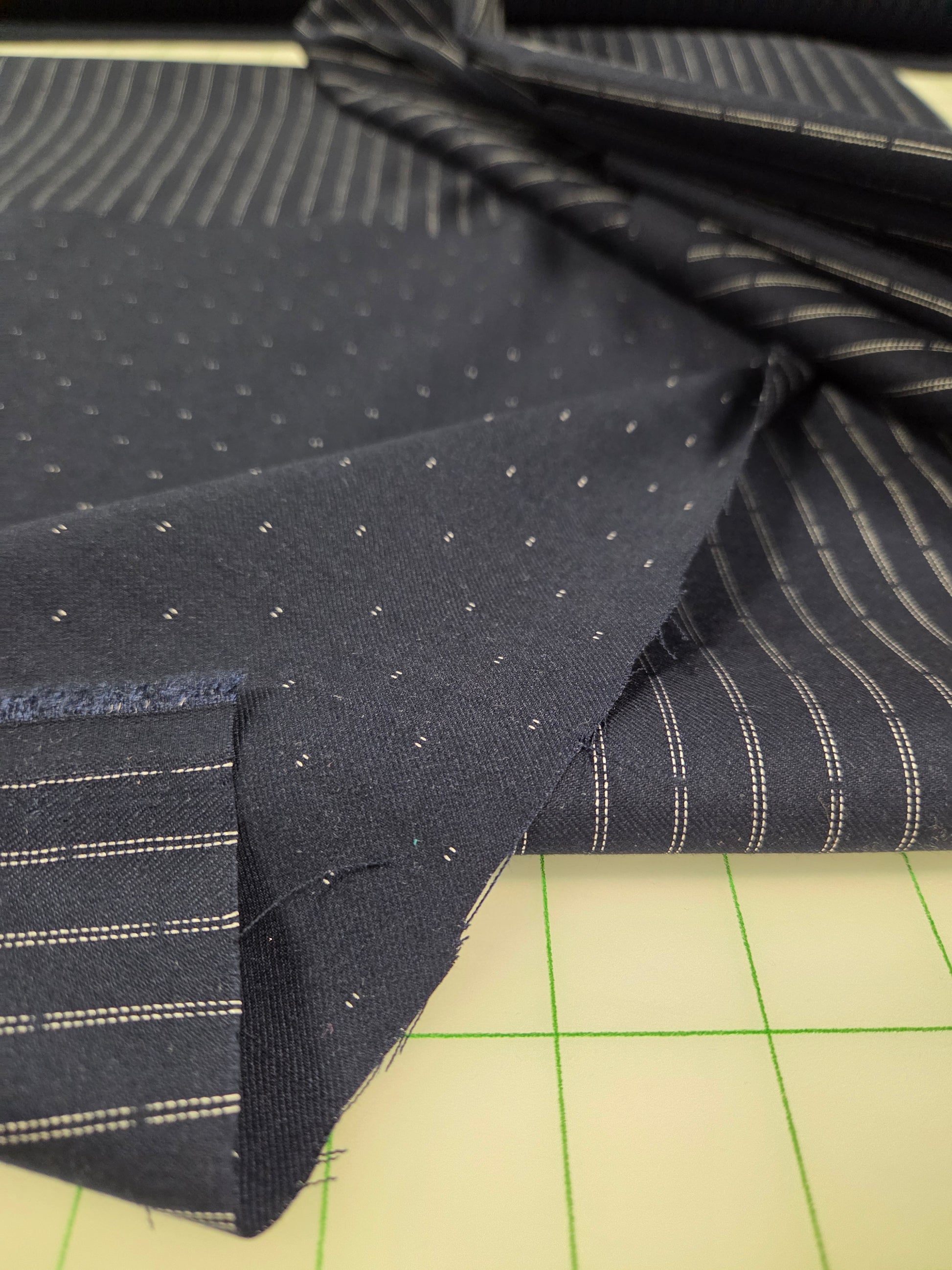 Close-up of black fabric with white dots and stripes on a cutting mat.
