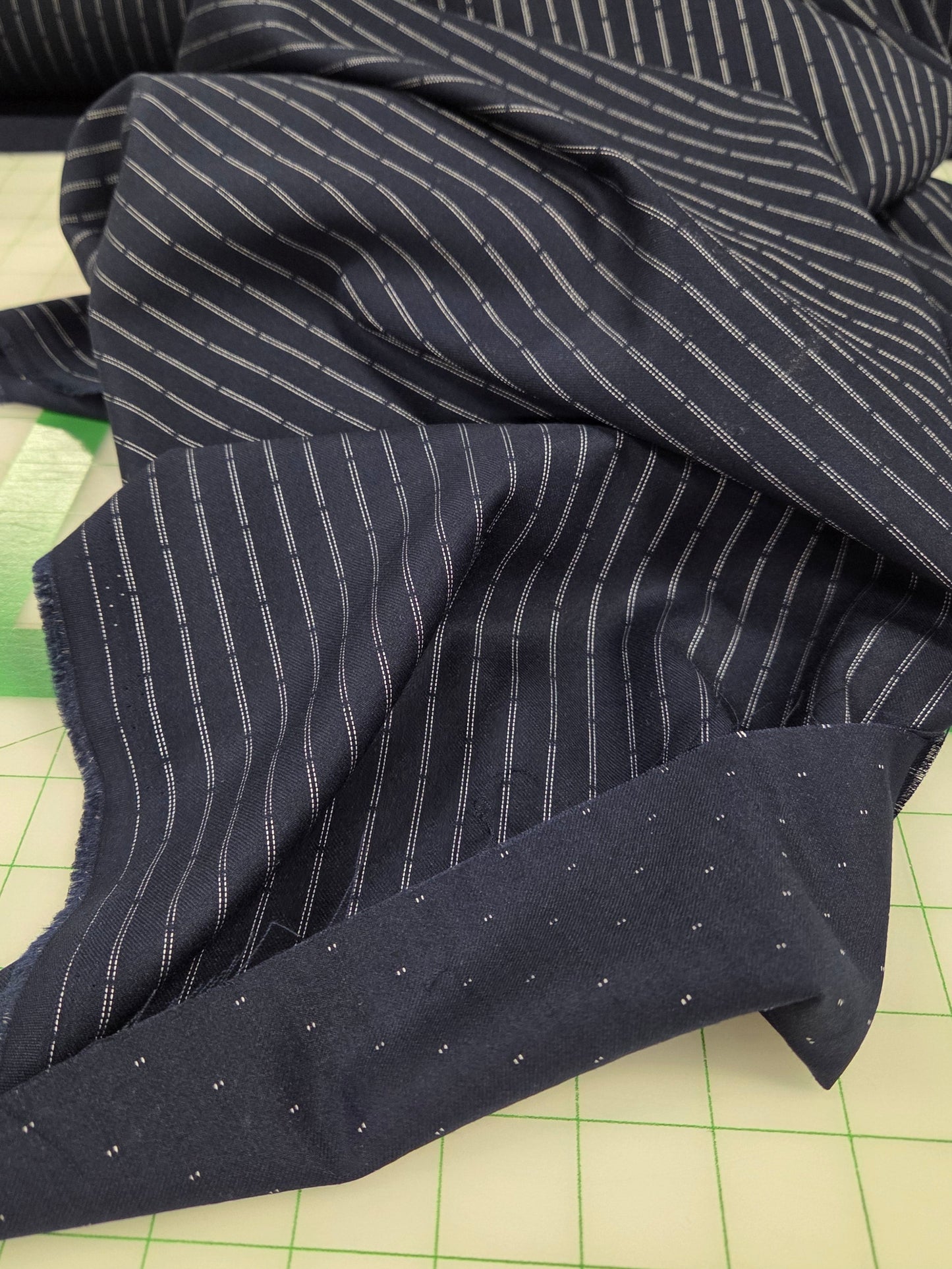 Dark blue fabric with white stripes on a green cutting mat