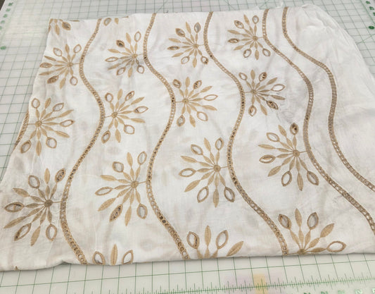 Fabric with gold embroidery on a cutting mat with measurements