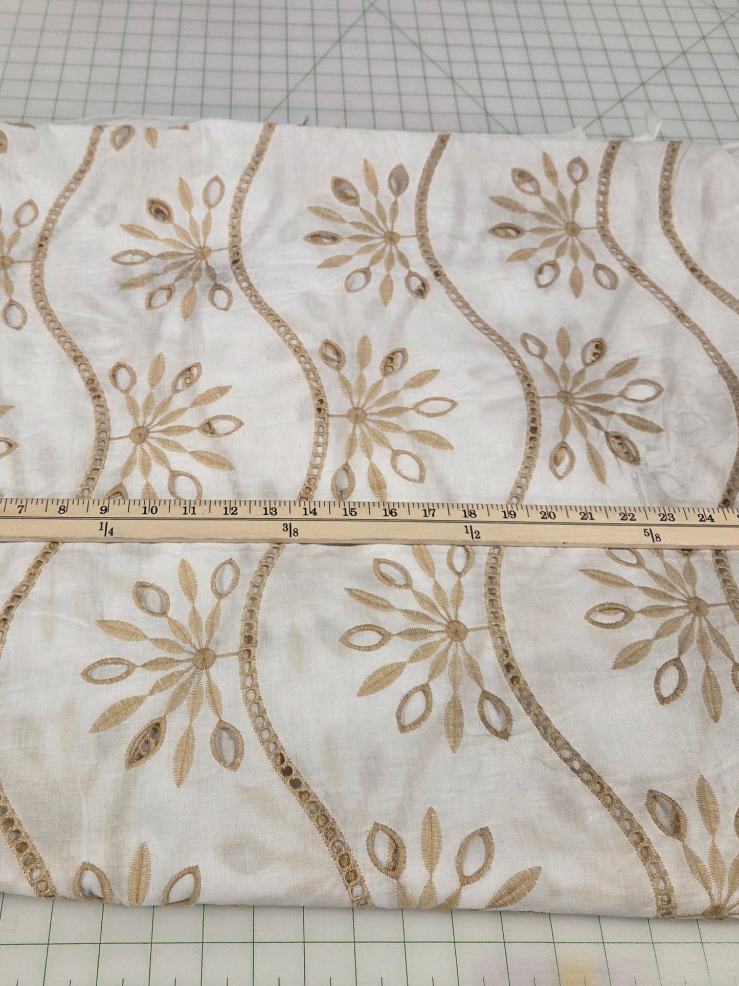 Decorative fabric with gold patterns on a cutting mat with measurements