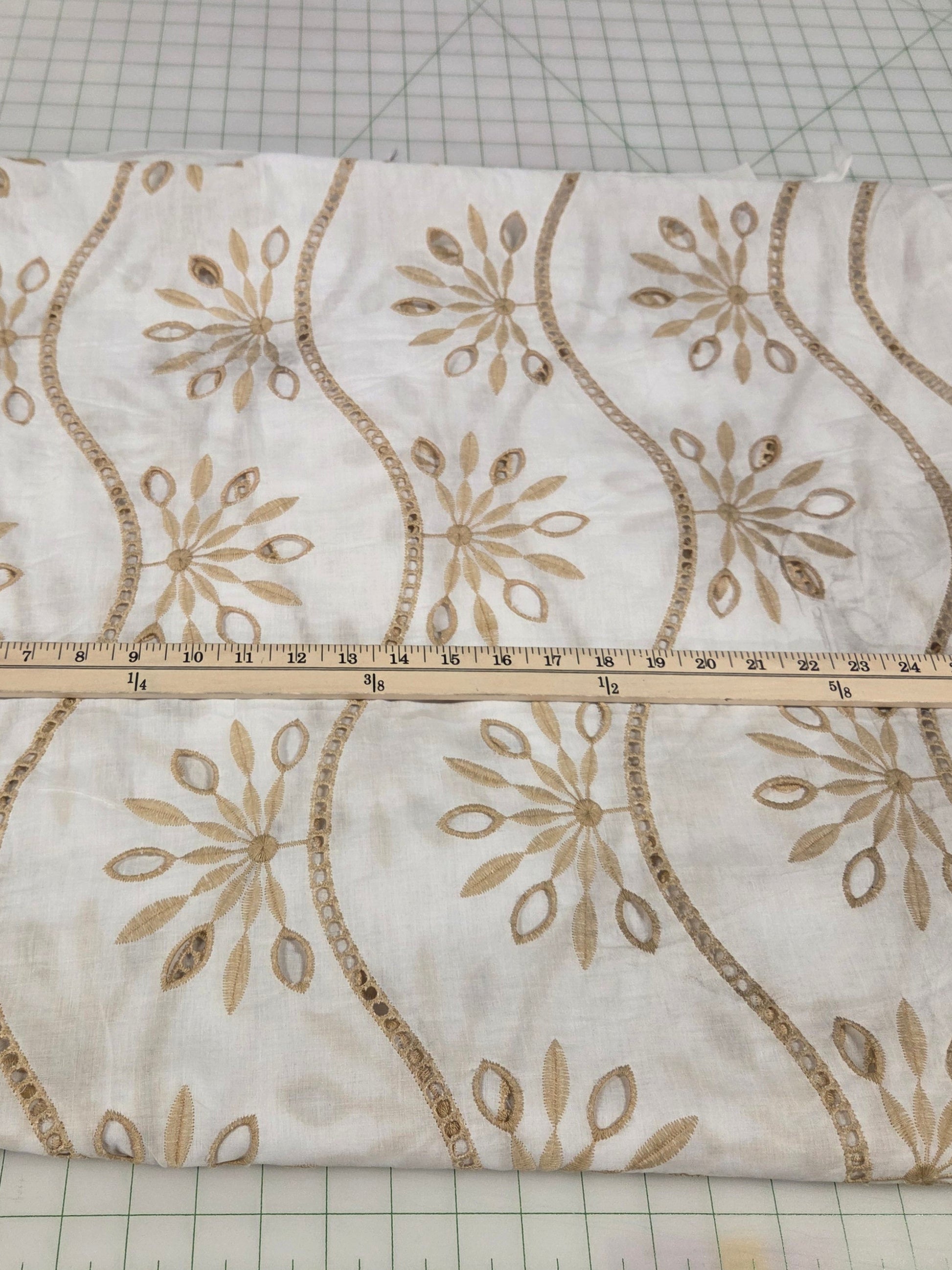 Decorative fabric with gold patterns on a cutting mat with measurements