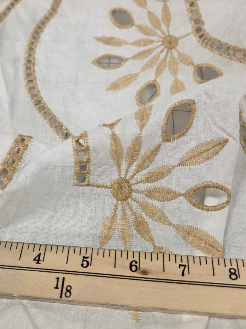 Embroidered fabric with gold patterns on a white background, measured by a wooden ruler.