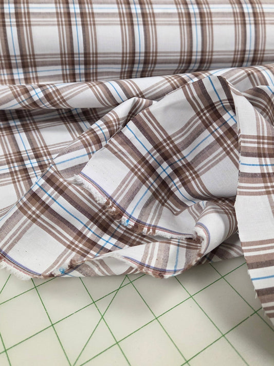 Plaid fabric on a cutting mat with sewing tools in the background