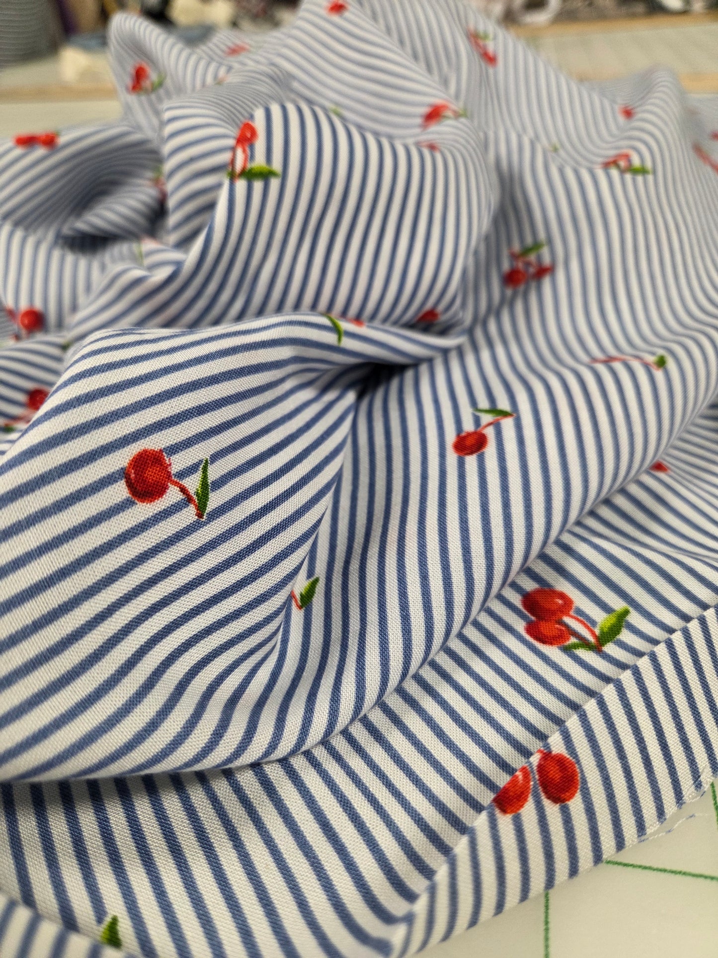 Blue and white striped fabric with cherry patterns on a blurred background