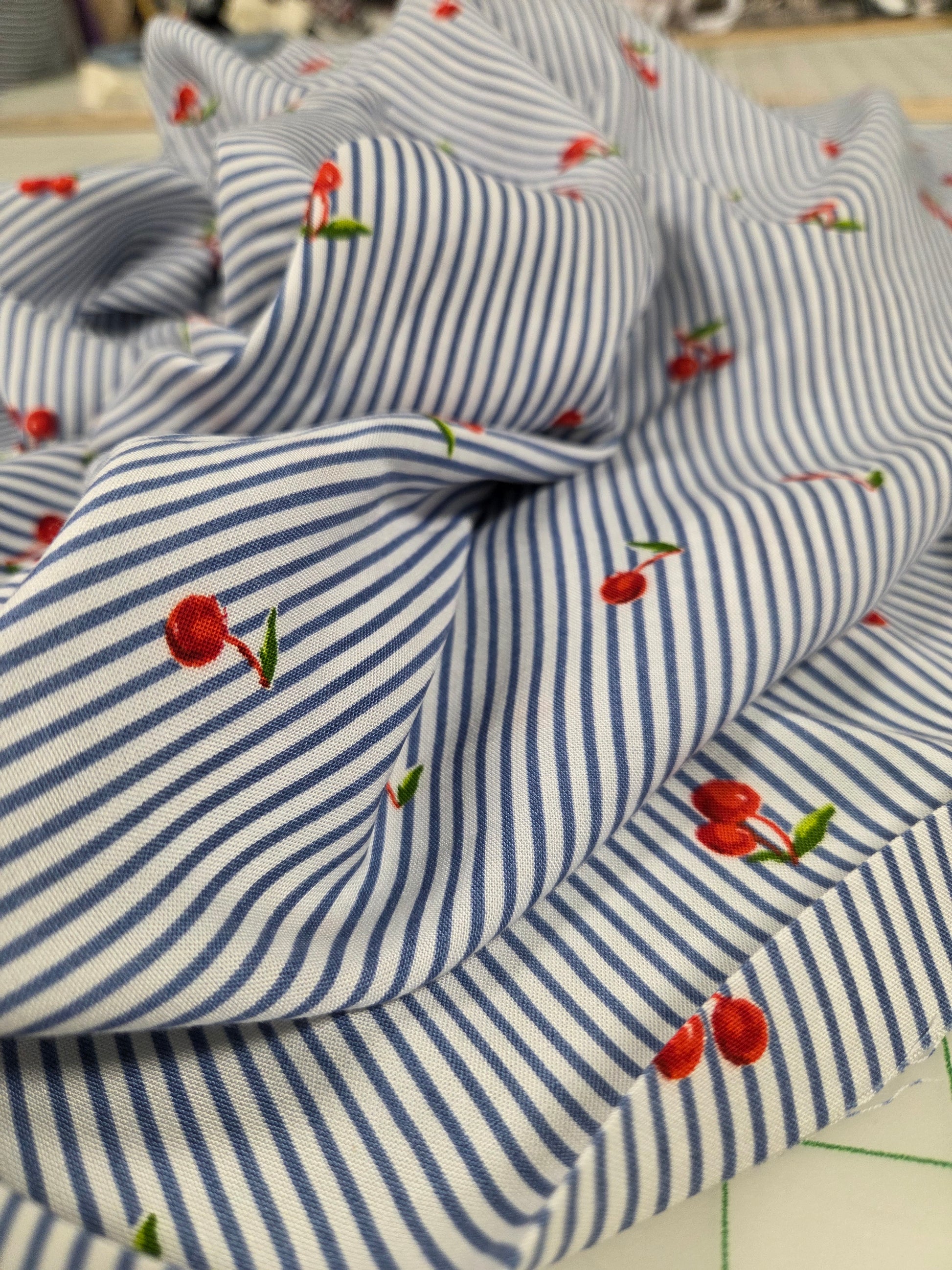 Blue and white striped fabric with cherry patterns on a blurred background