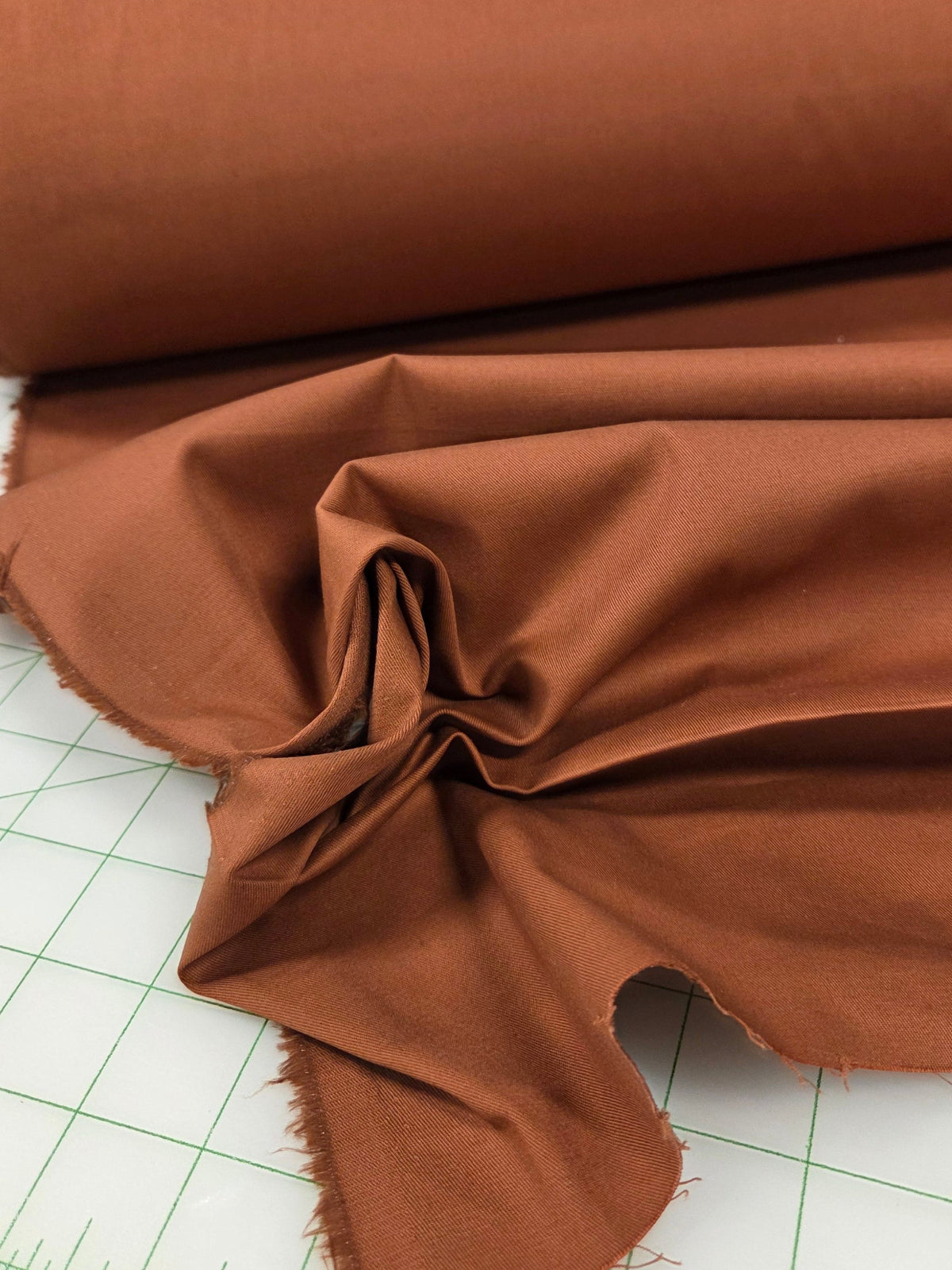 Brown fabric on a cutting mat with grid lines