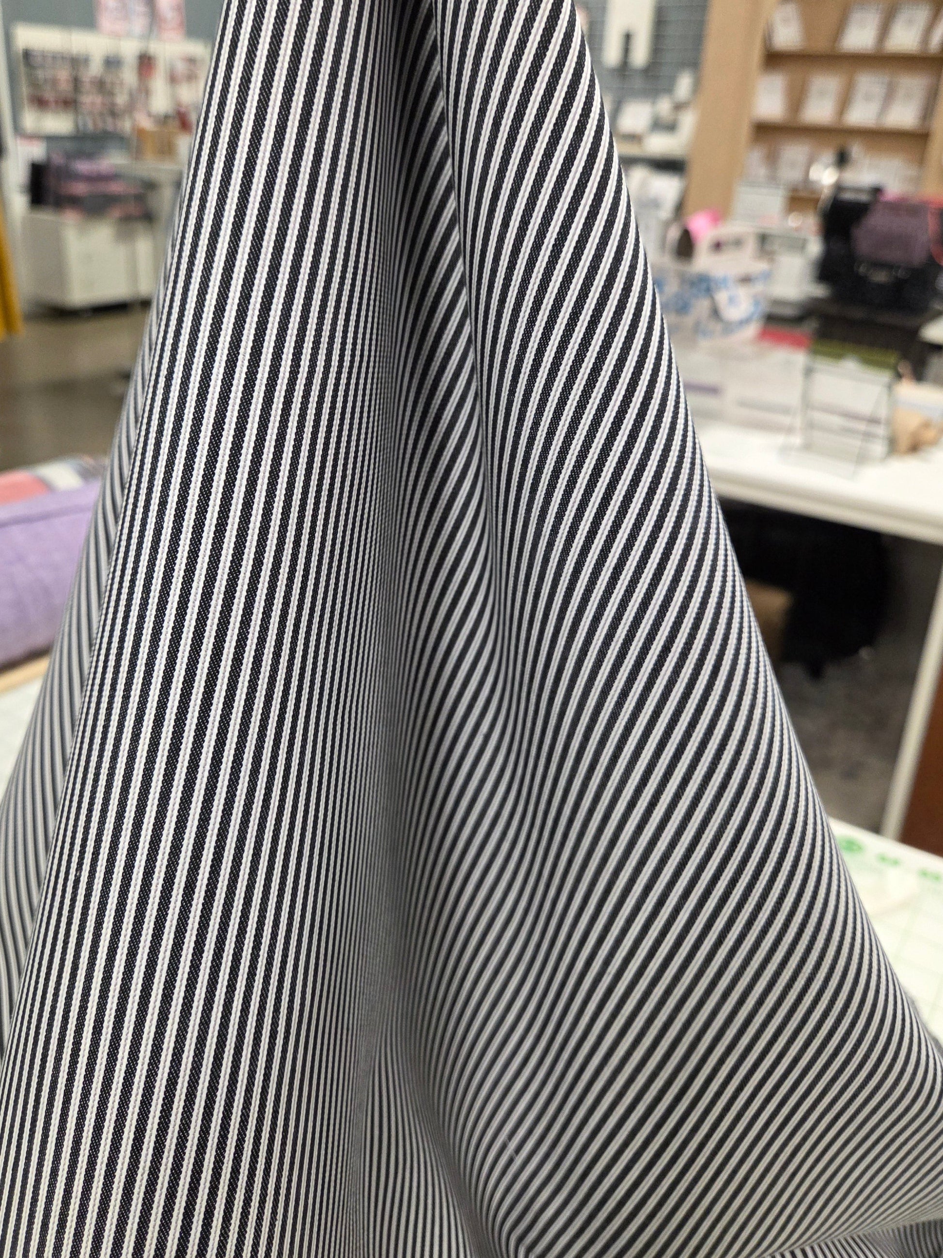 stripe held up to show drape, cotton woven with slight stretch, has some drape and slight crisp to fabric