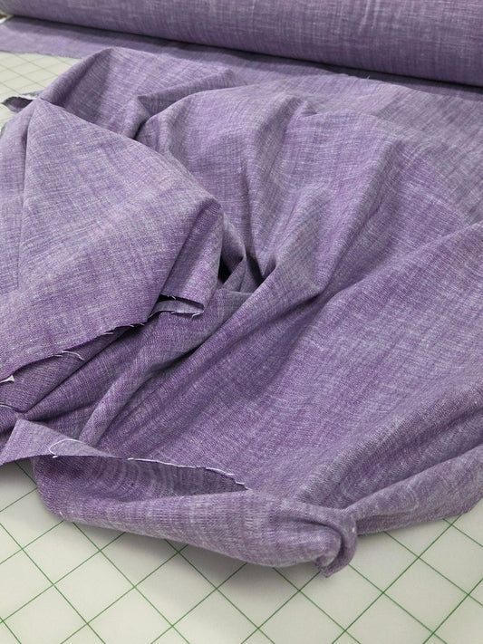Purple fabric on a cutting mat with a store in the background
