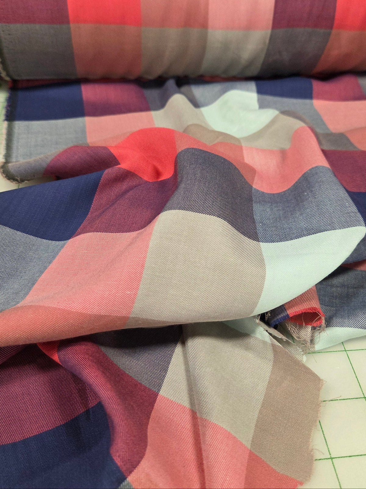 Plaid fabric swatches in various colors on a cutting mat.