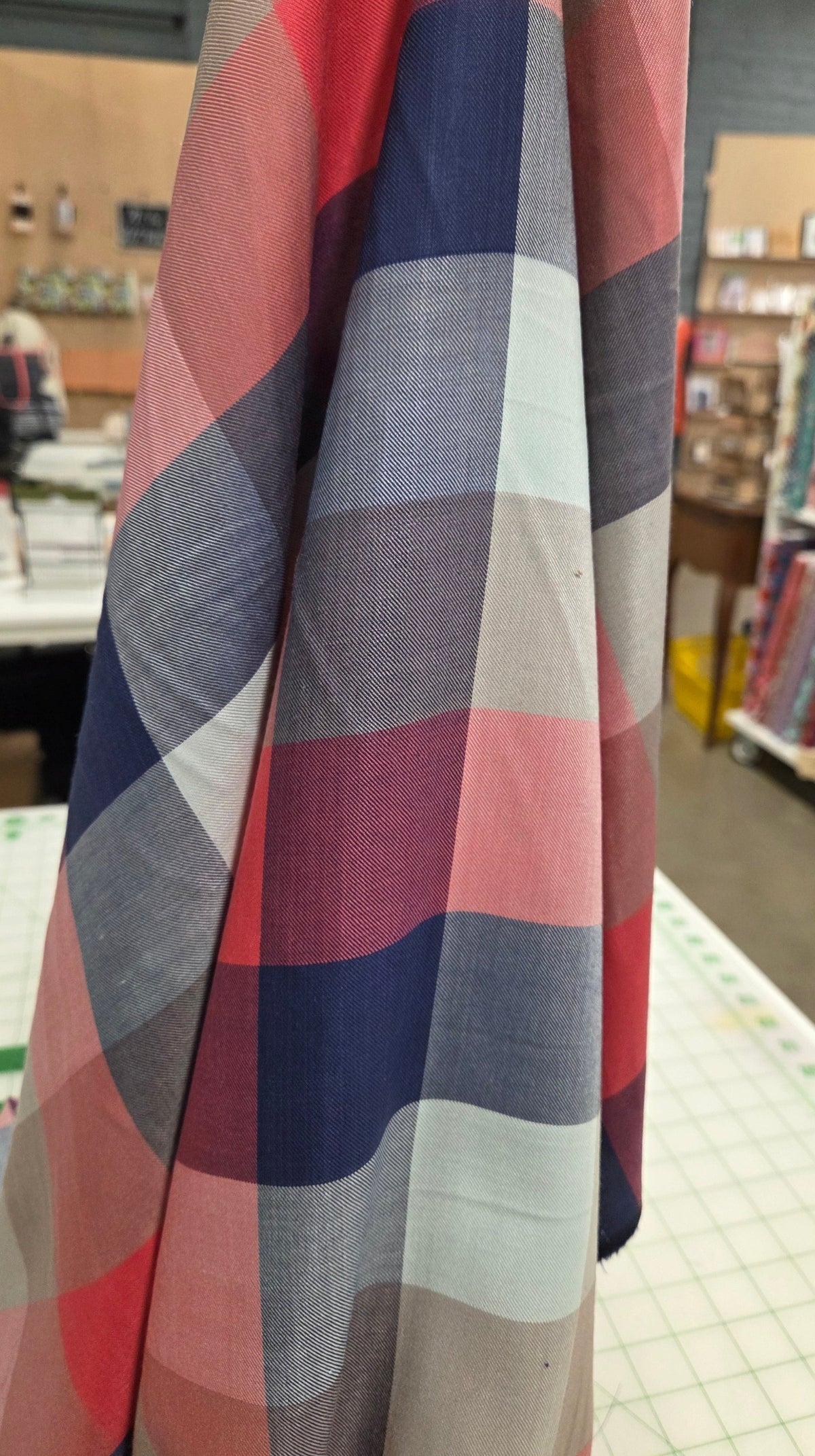 Plaid fabric with red, blue, and gray pattern in a store setting
