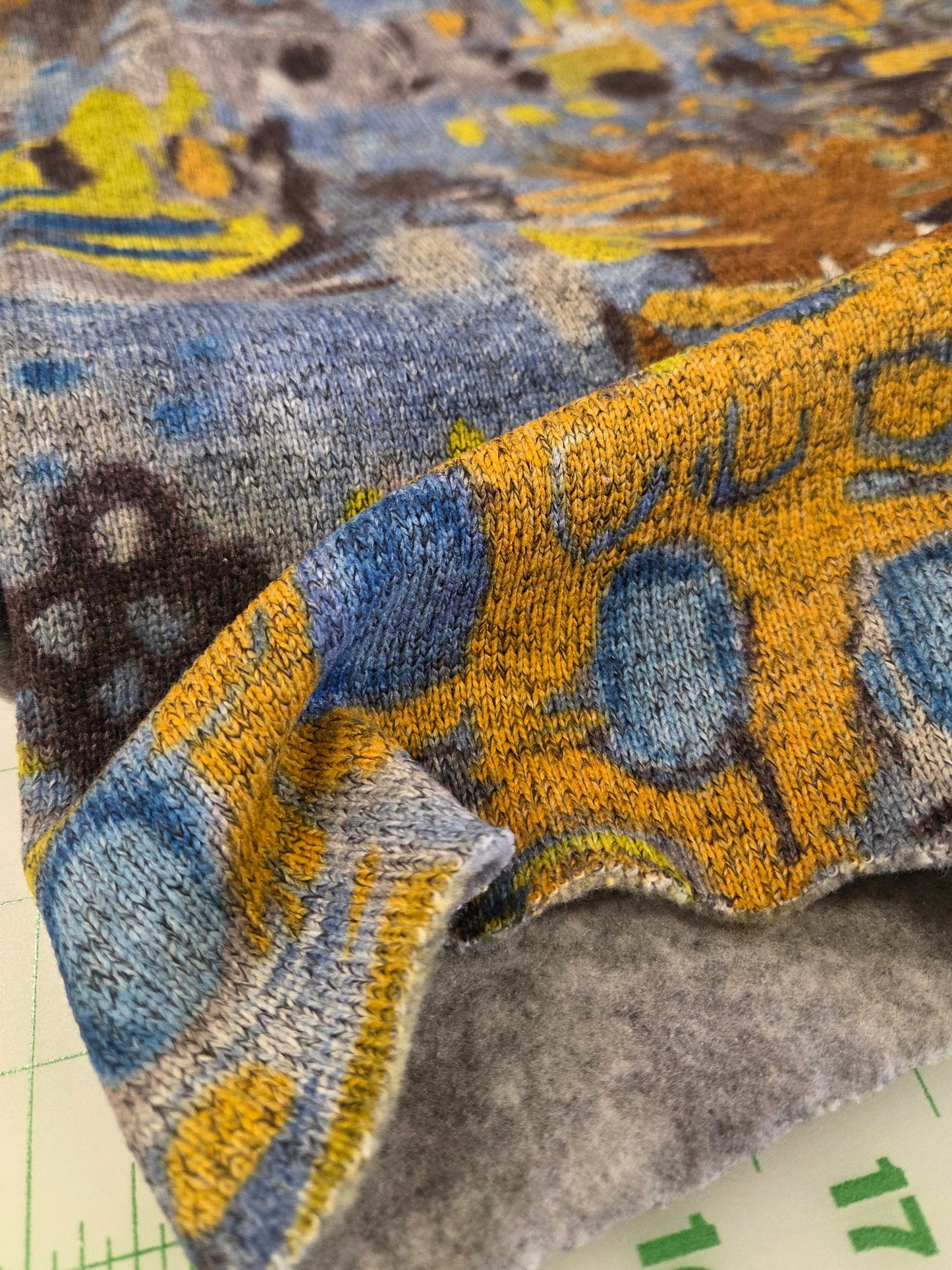 Close-up of a textured fabric with blue and yellow patterns on a grid background
