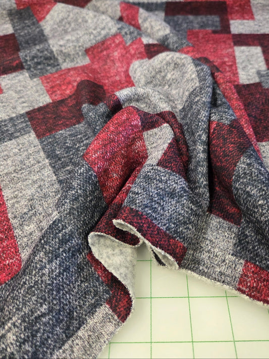 Plaid fabric with red, gray, and blue pattern on a cutting mat